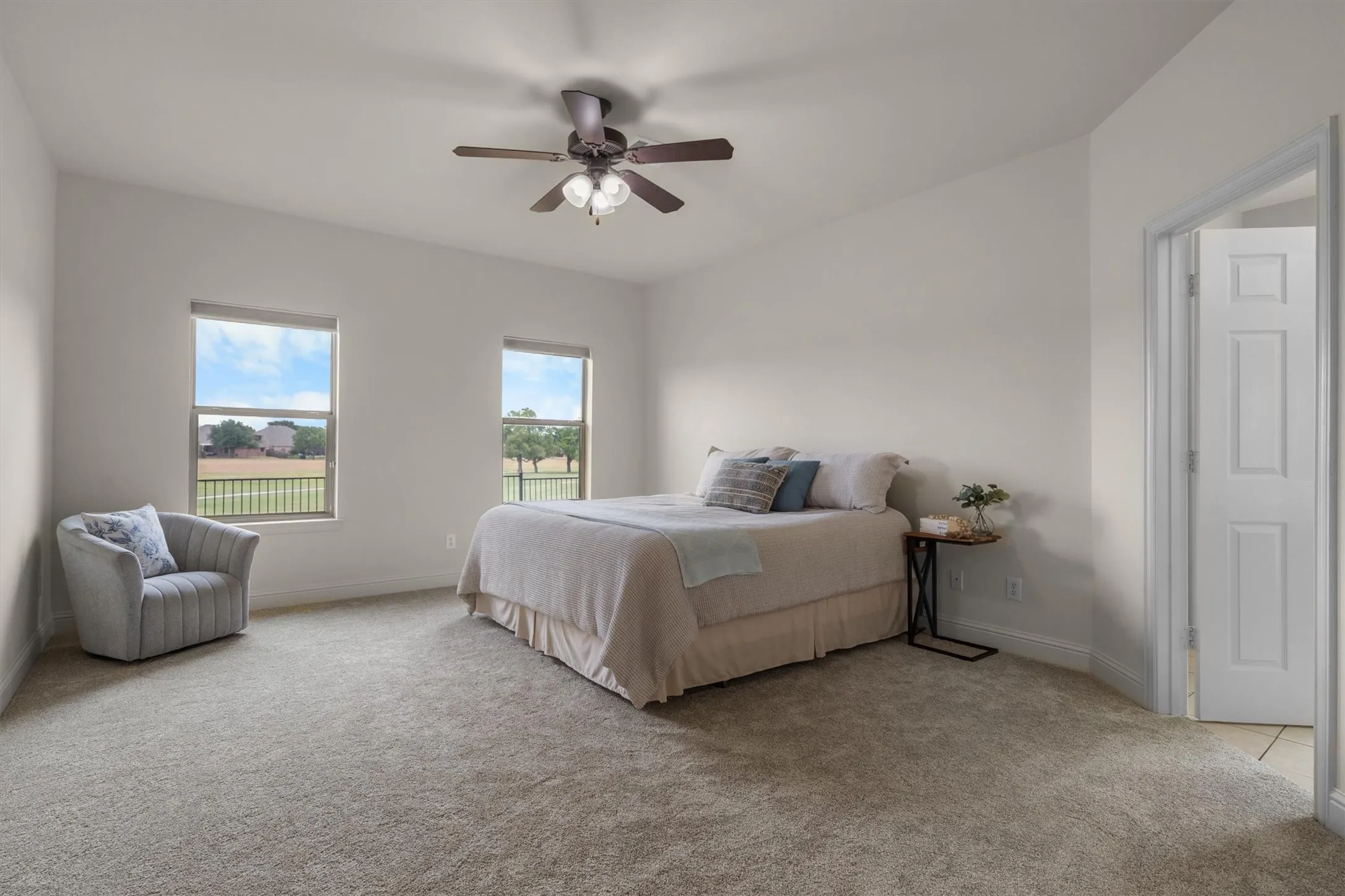 Spacious bedroom with dual windows, ceiling fan, and cozy sitting nook