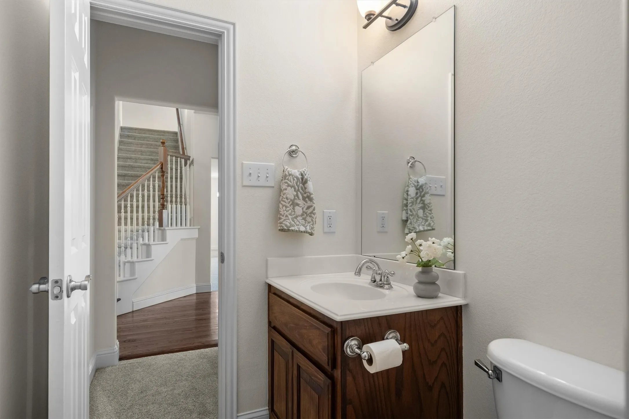 Full bathroom with vanity, mirror, and easy access to the staircase and living areas