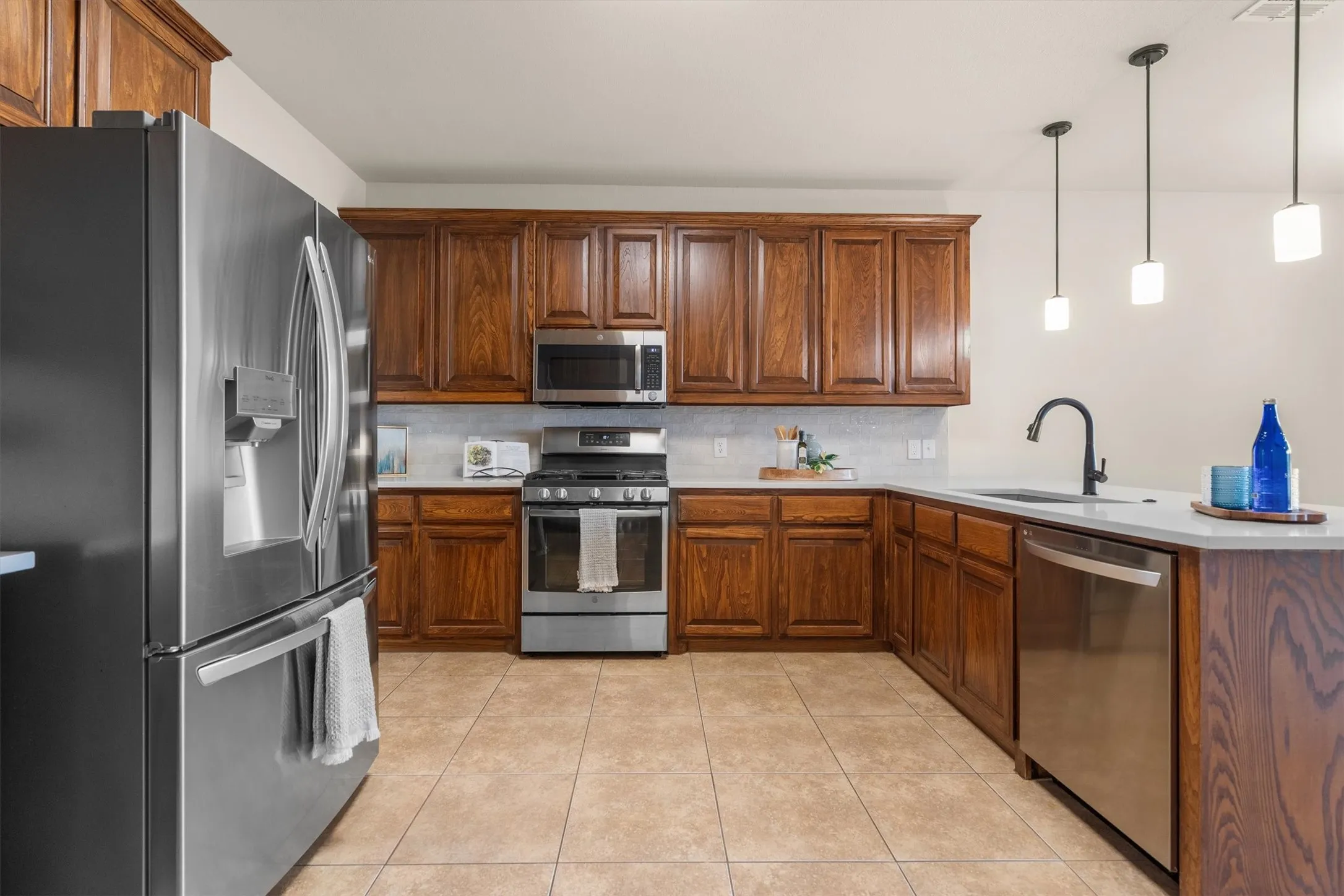 Well-appointed kitchen with stainless refrigerator, dishwasher, and abundant cabinetry