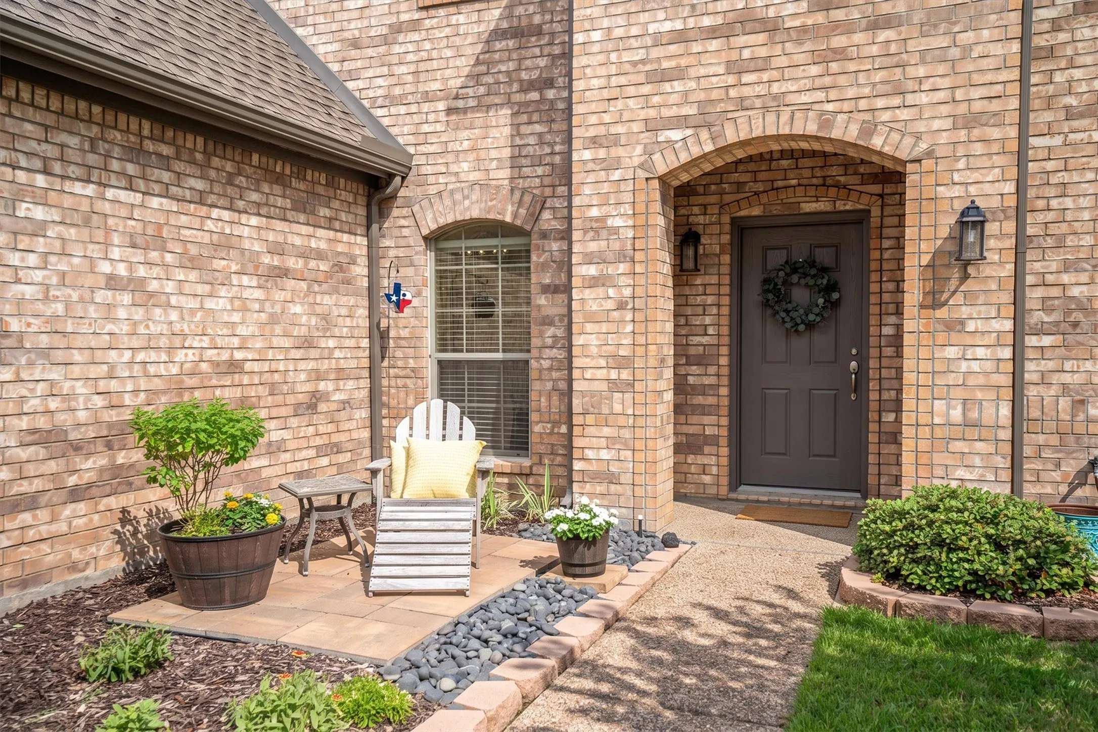 Covered front porch with brick archway, statement door, and cozy seating