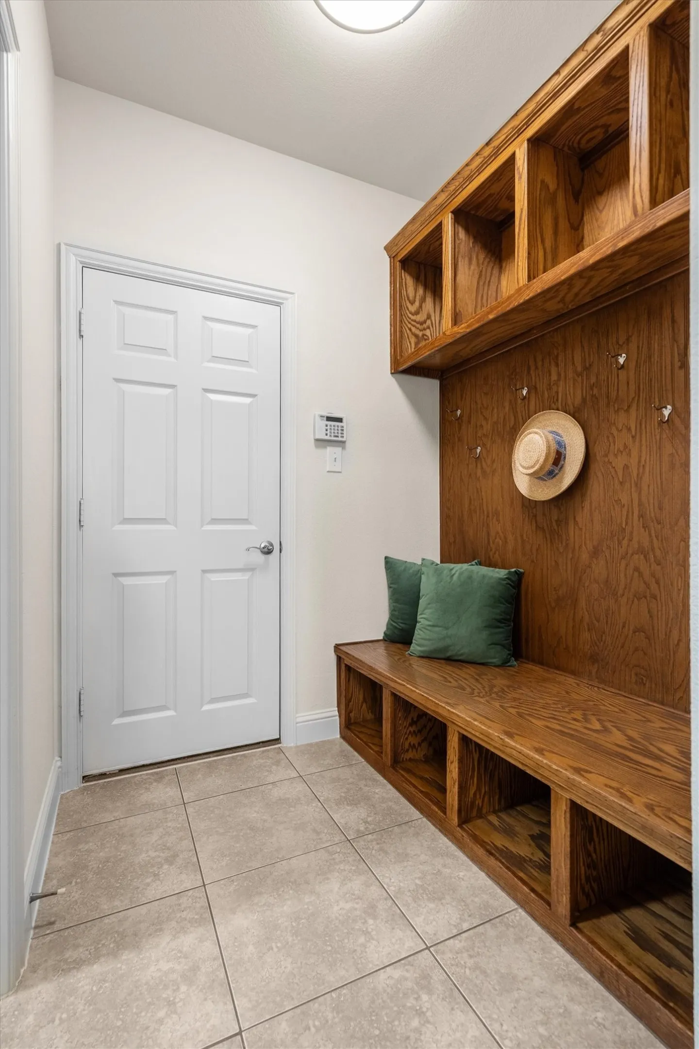 Practical mudroom with bench seating, hooks, and tile flooring