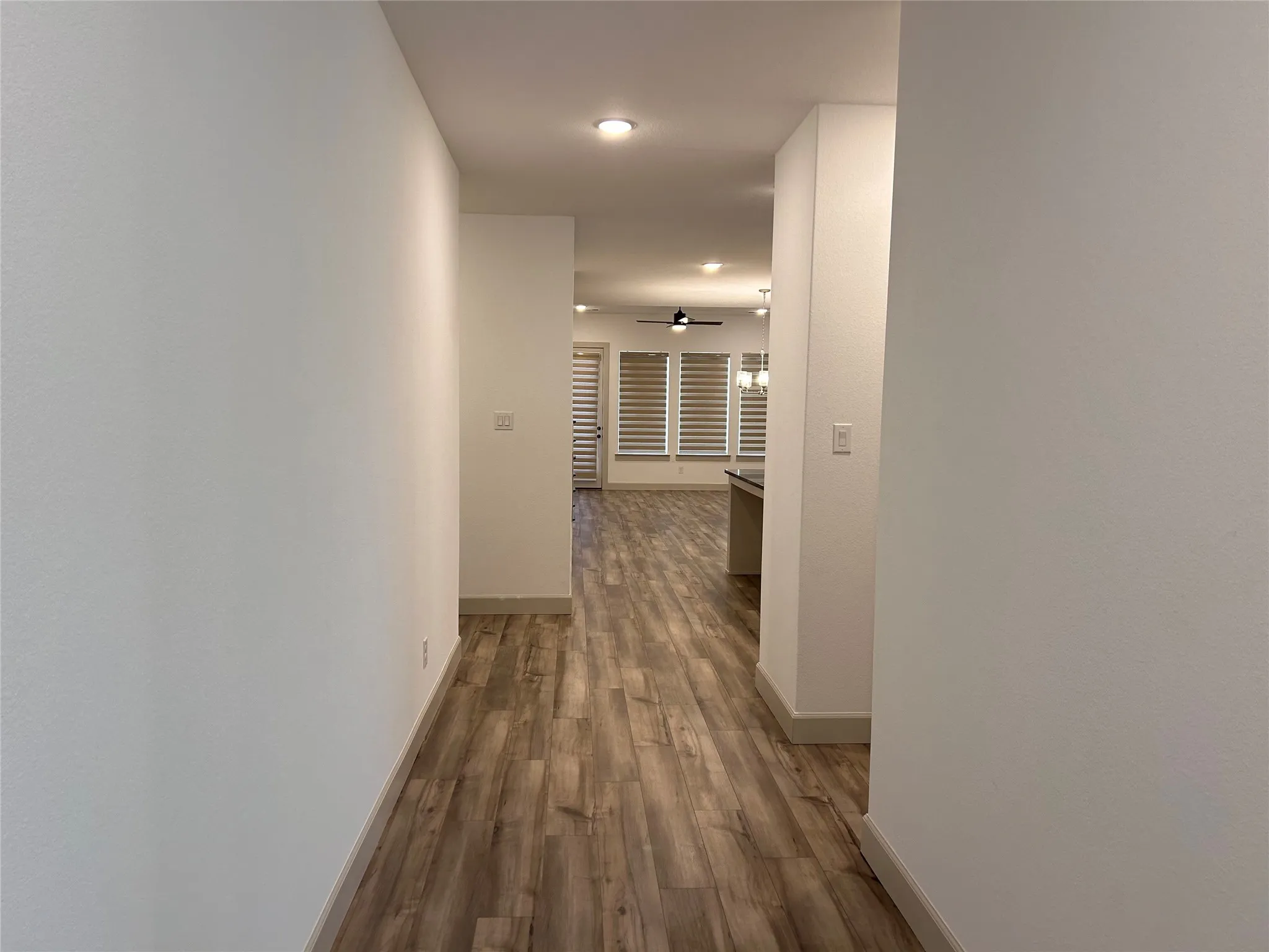 Recessed lighting illuminates wood-finish flooring throughout the space