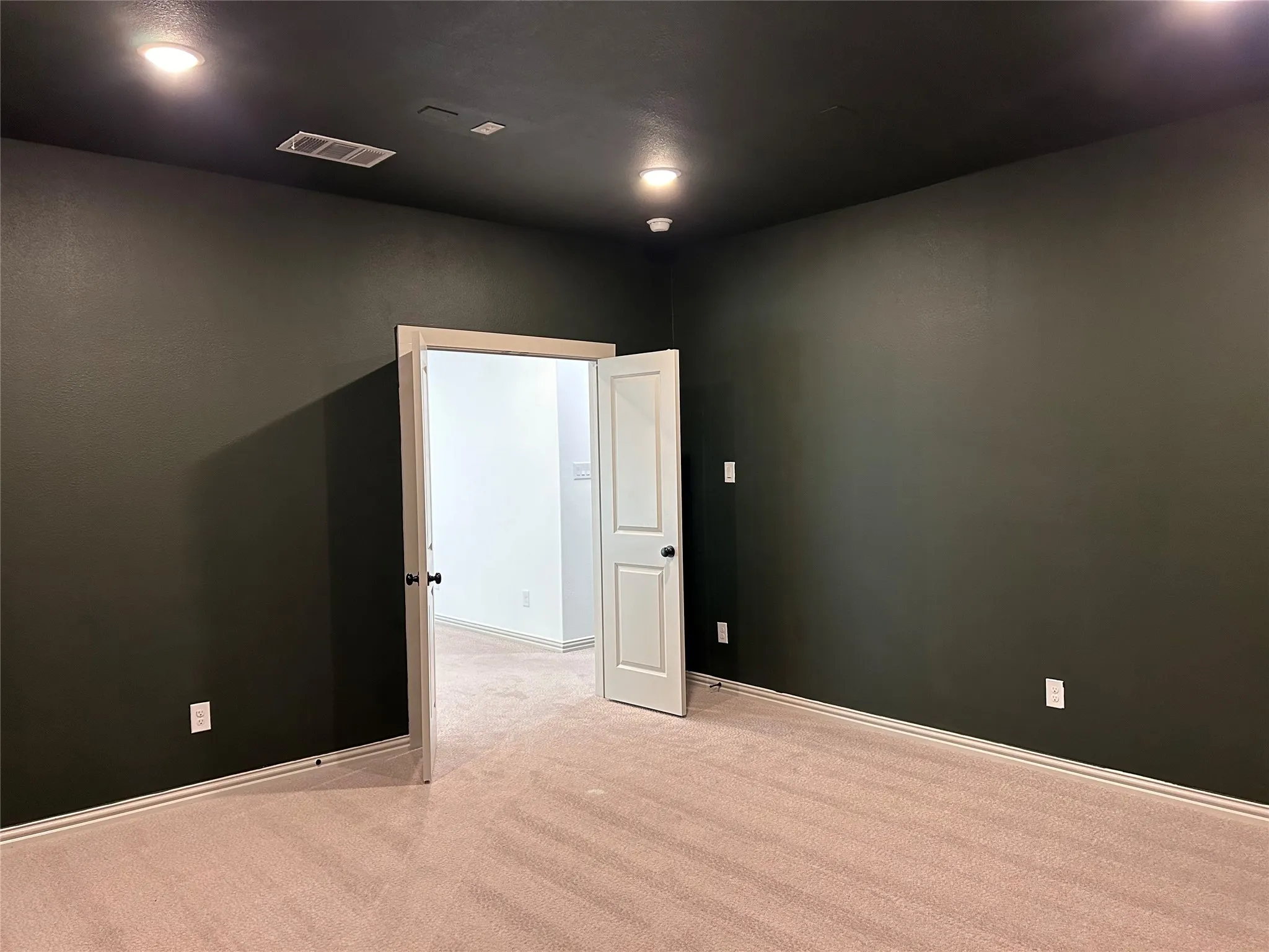 Recessed lighting, dark painted walls, neutral carpeting, and white trim