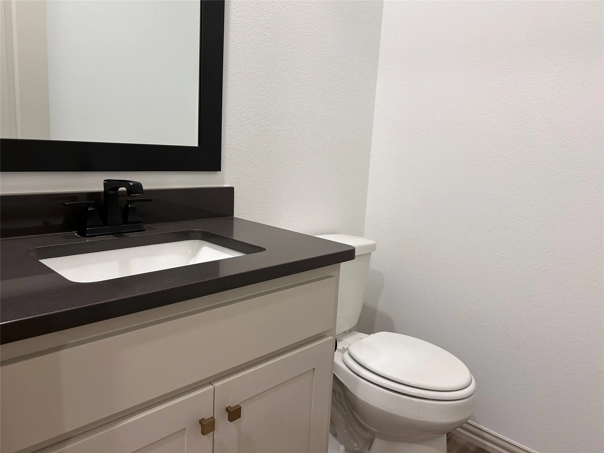 White vanity with a dark countertop and integrated sink