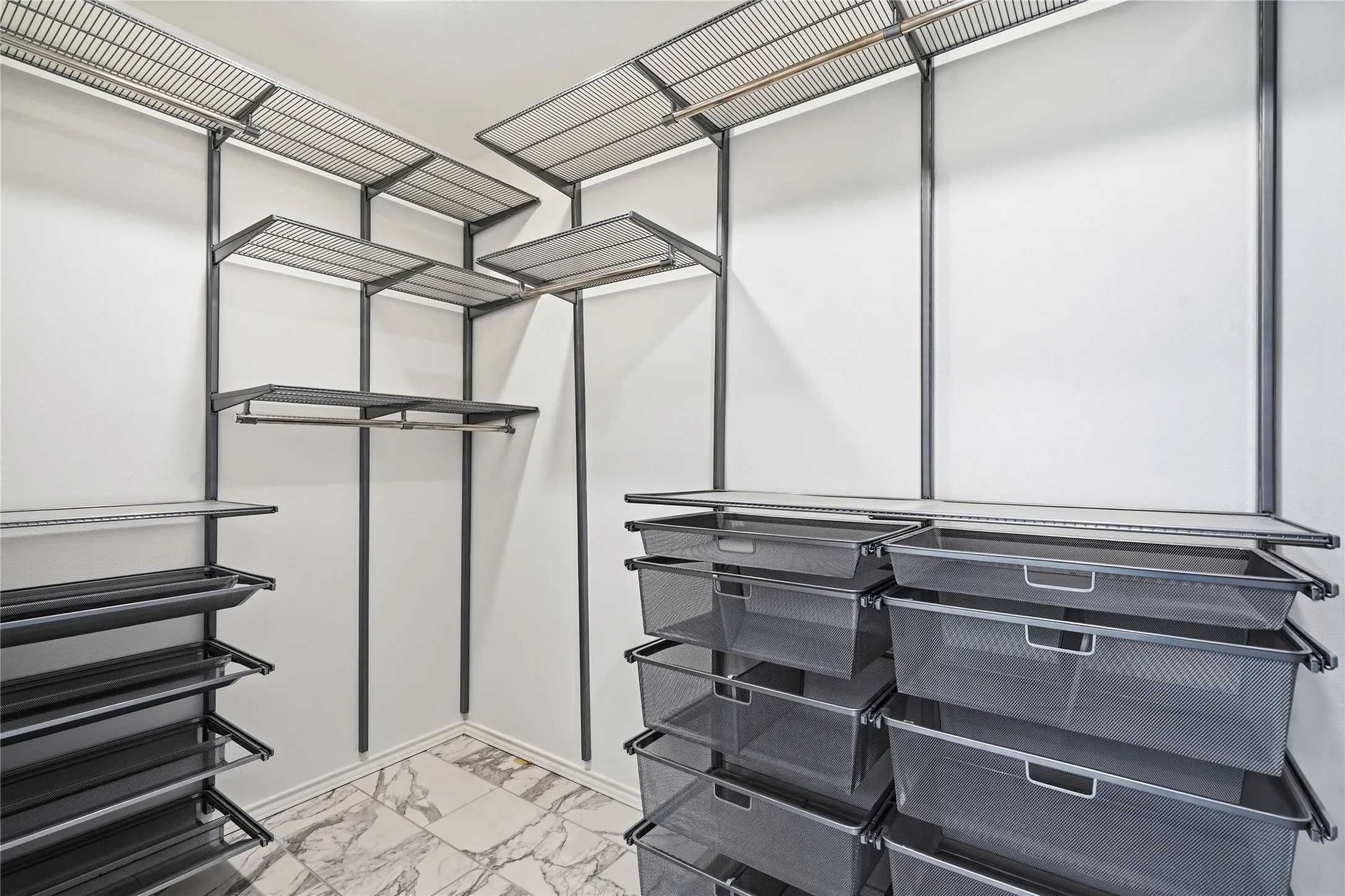 Custom walk-in closet with metallic shelving system, hanging rods, pull-out mesh drawers, and marble tile floor