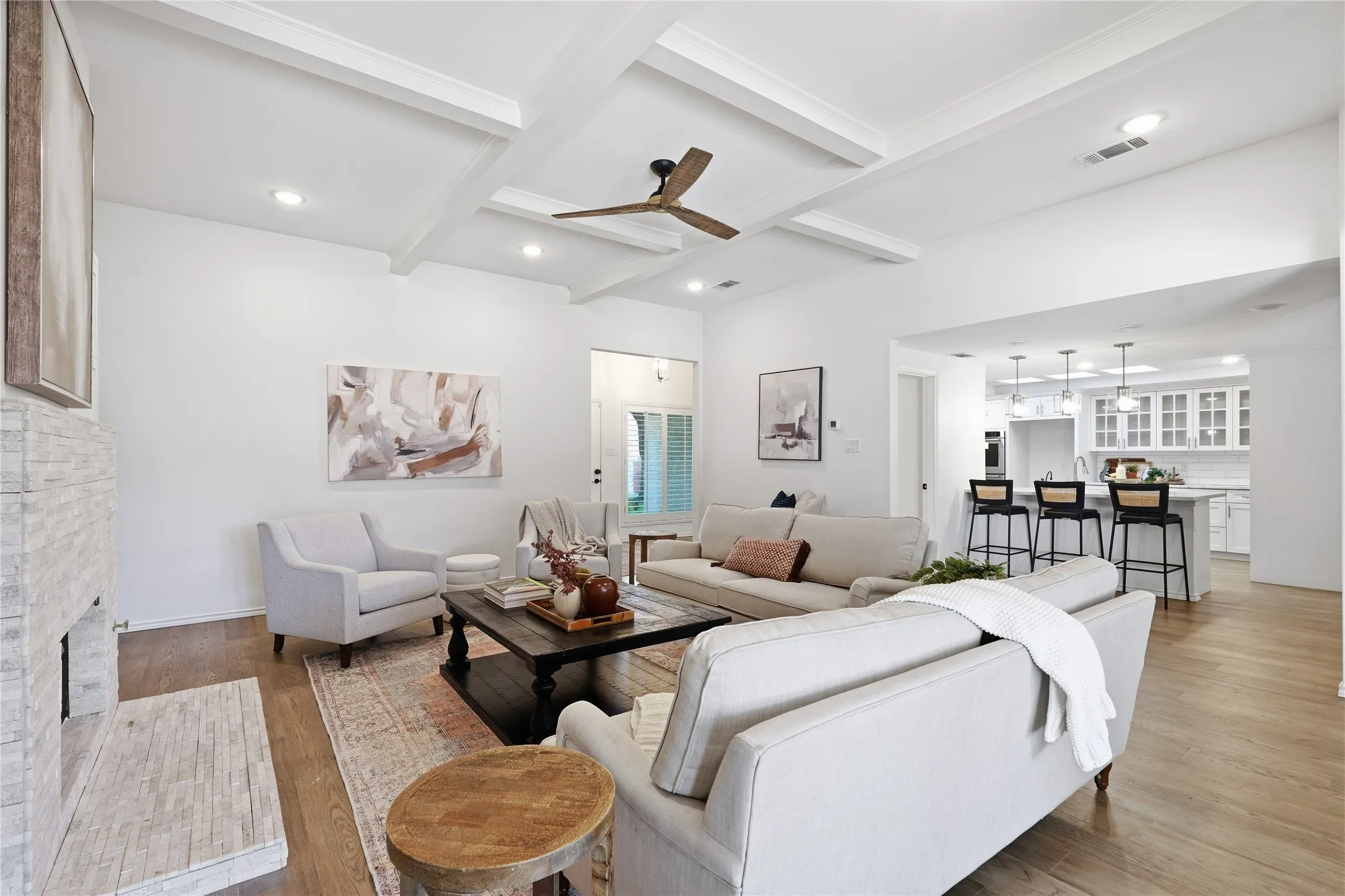 Modern living room with white coffered ceiling, stacked stone gas fireplace, and custom wet bar with wine fridge