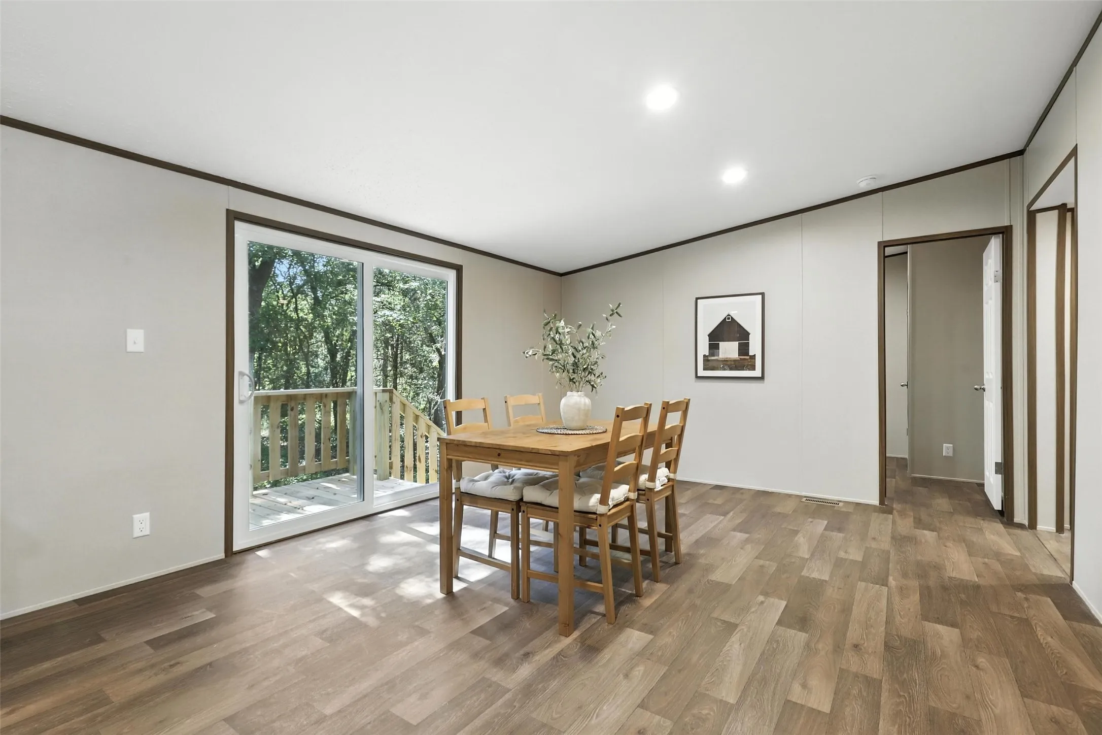 Wood-finish flooring, recessed ceiling lighting, and a sliding glass door providing outdoor access to a wood deck