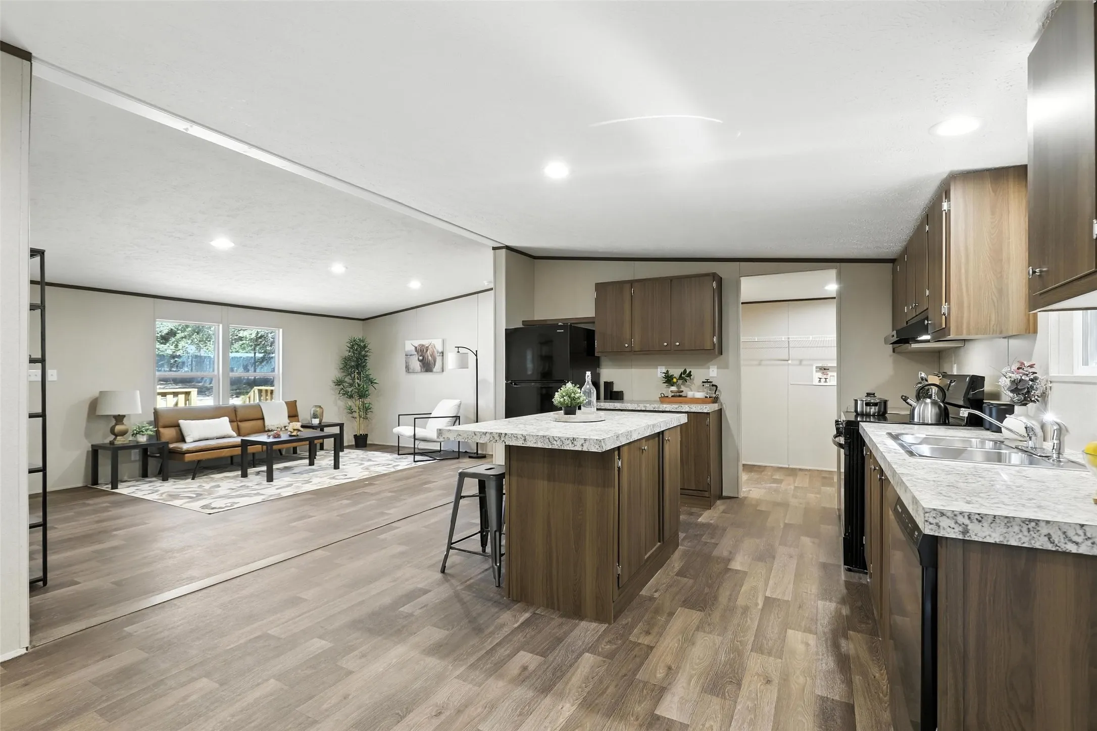 Kitchen featuring an island with a light-colored countertop, wood-finish cabinetry, and a stainless steel sink