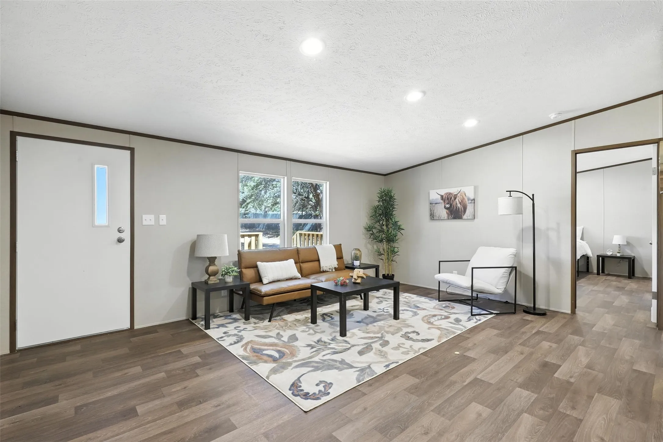 Wood-finish flooring, recessed lighting, and multiple windows illuminate the living area