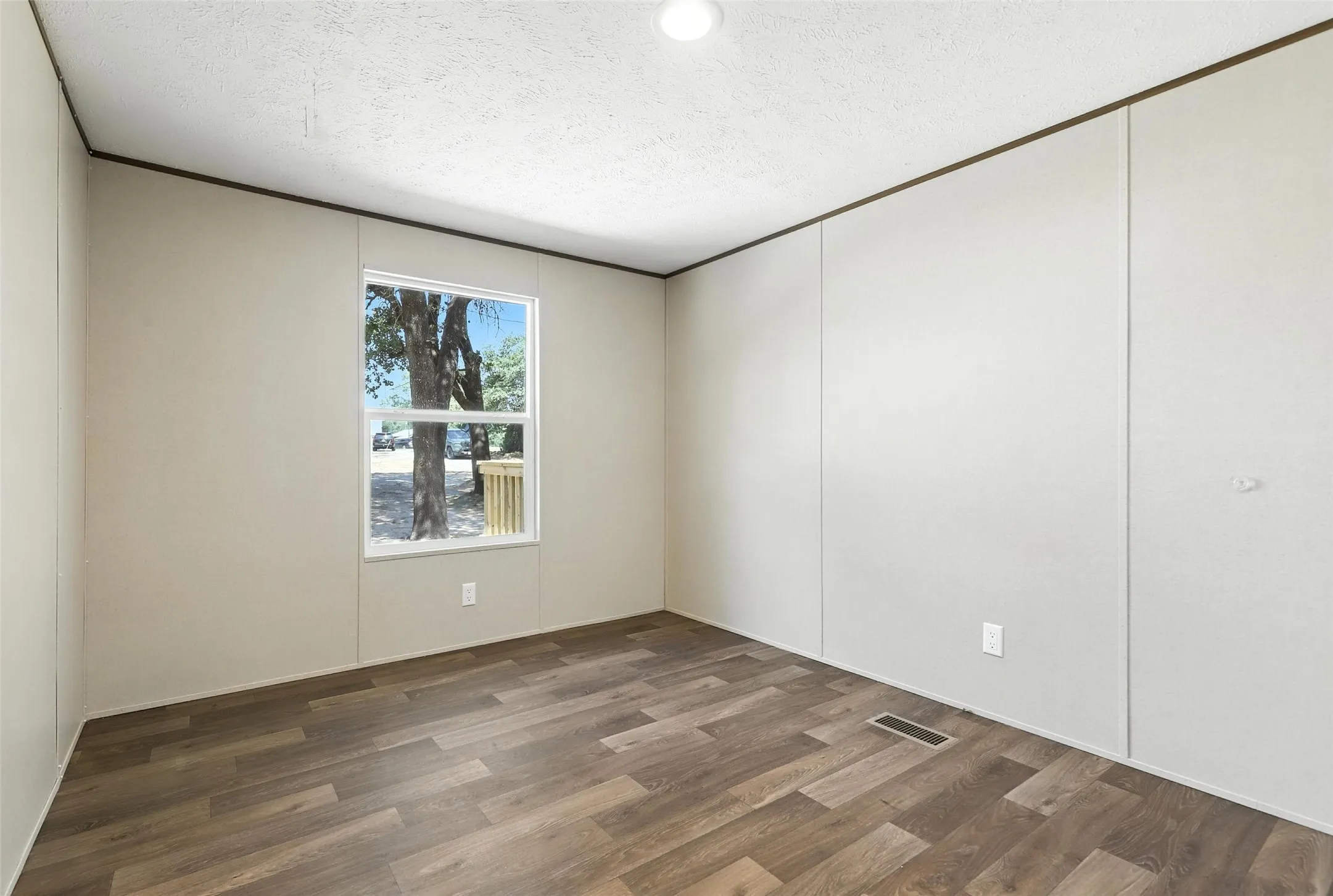 Wood-finish flooring, white walls, and a window with a white frame