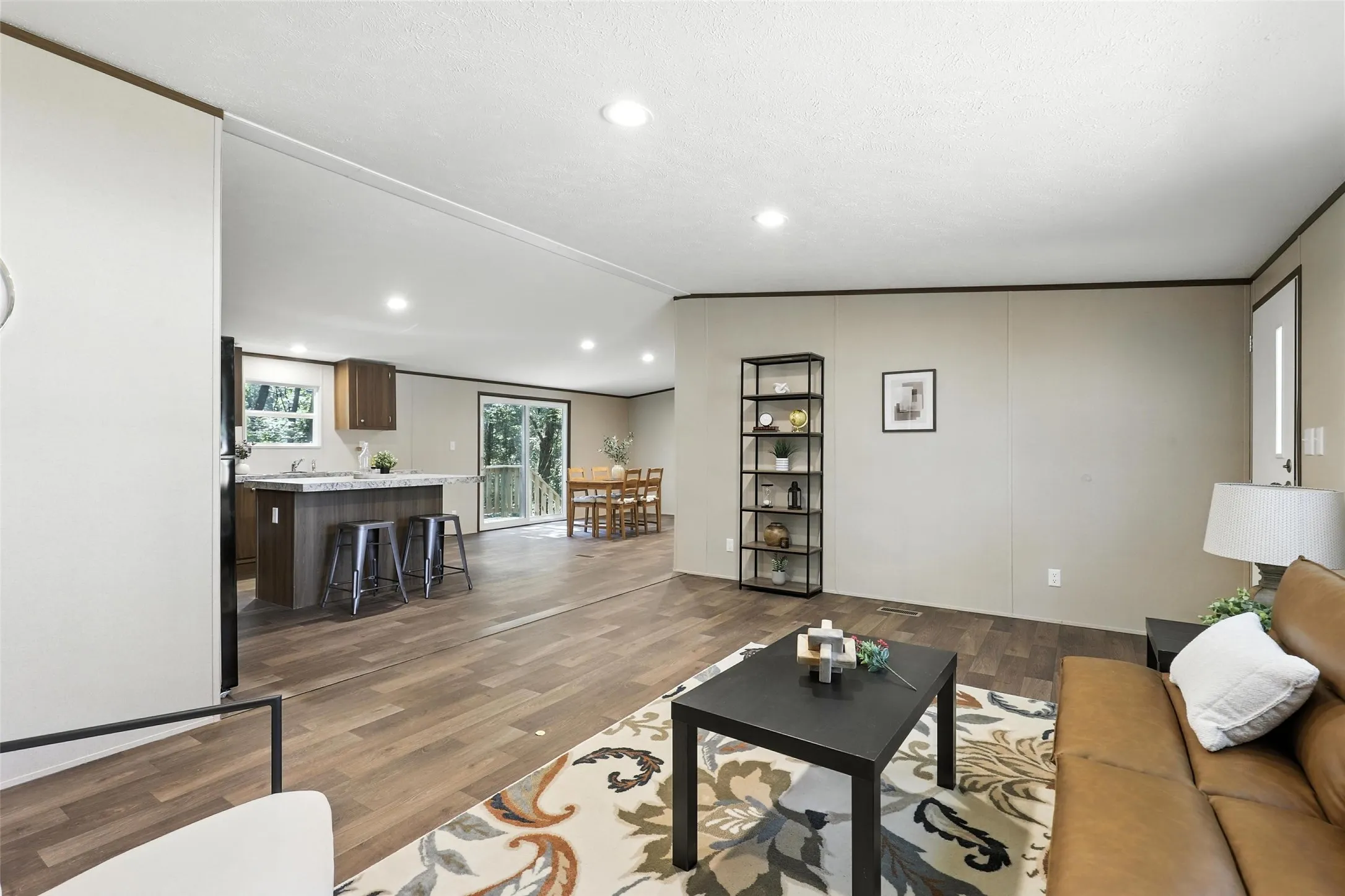Open-concept living space with wood-finish flooring, recessed lighting, and a kitchen island with seating