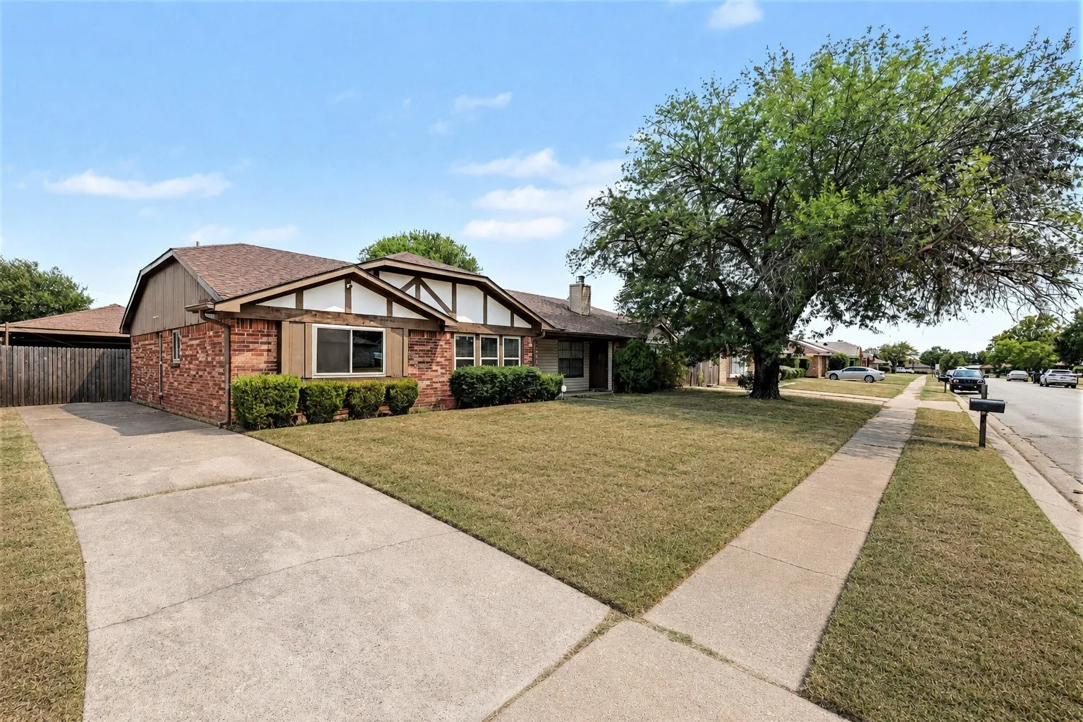 Brick exterior with decorative trim, mature front yard landscaping, concrete driveway, and established sidewalk