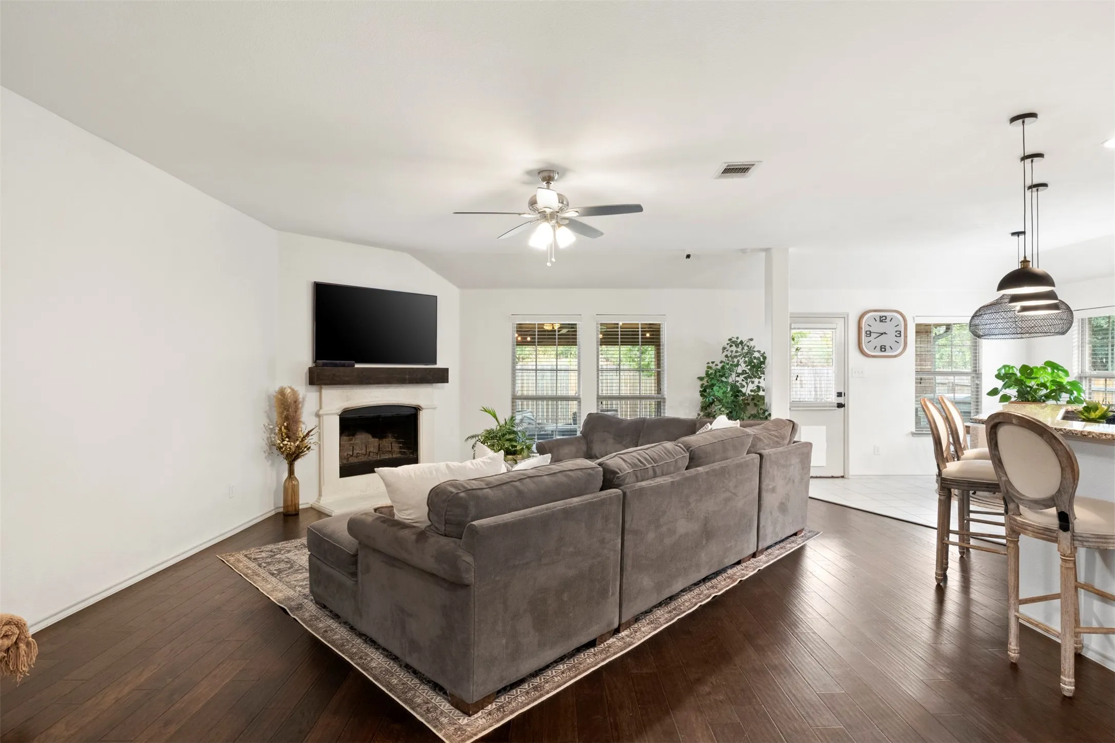A closer view of the WOOD-BURNING FIREPLACE and the wall of windows overlooking the backyard and extended covered porch—bringing natural light into the heart of the home.
