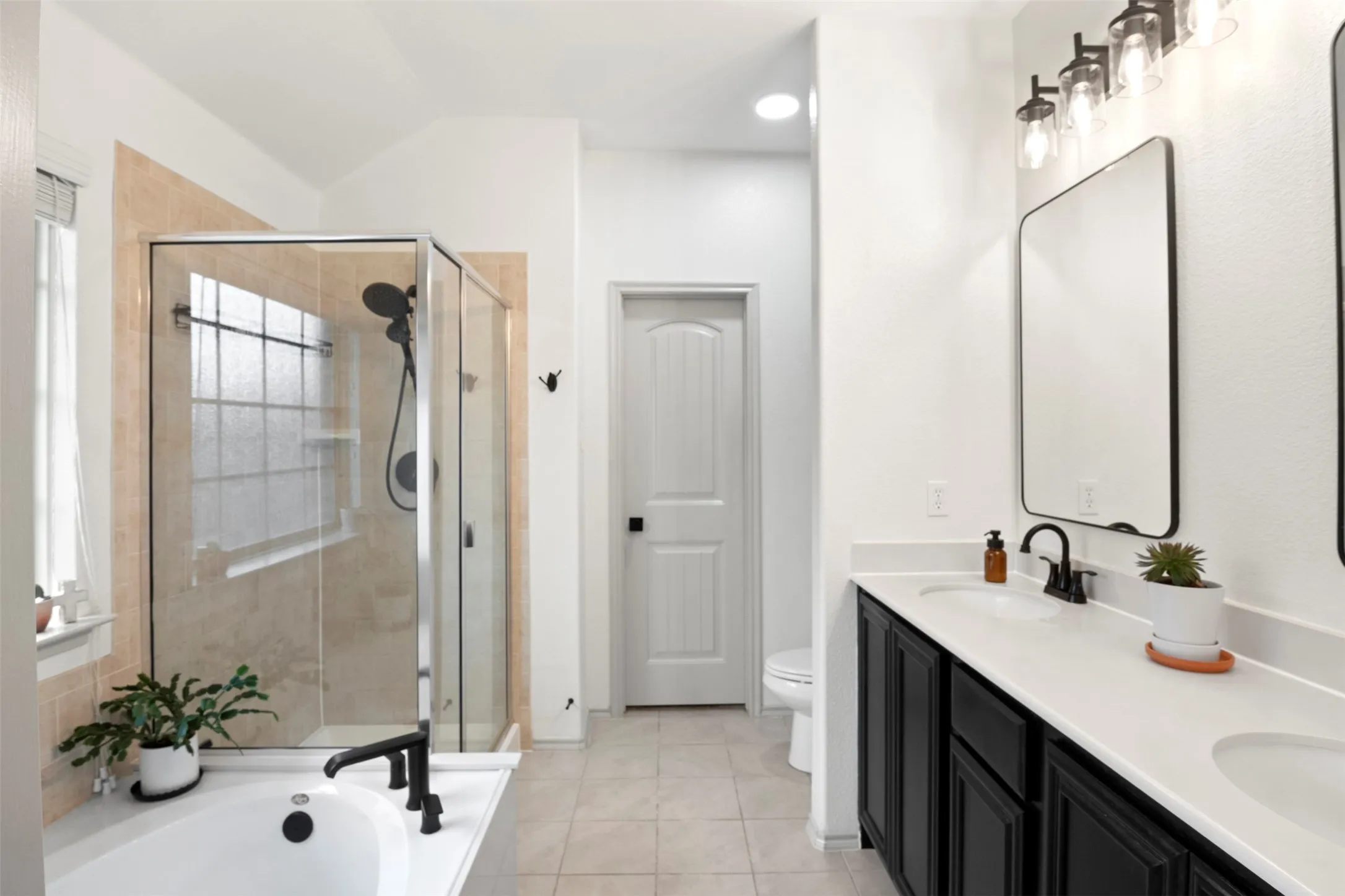 primary bath with dual sinks, separate soaking tub and separate shower. Updated black fixtures and mirrors give the space a clean, current look.