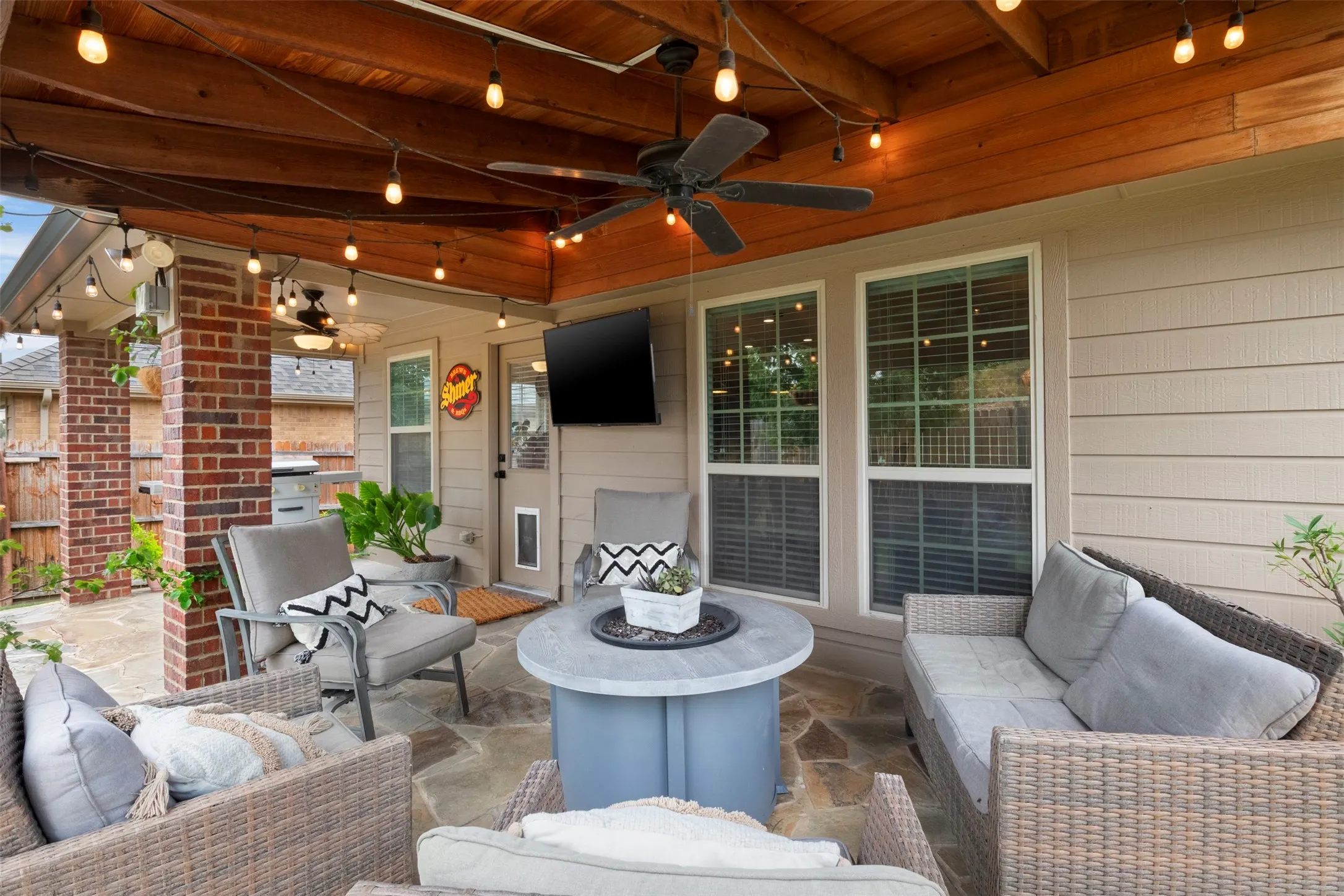 Flagstone flooring, overhead fan and string lighting make this covered space ready for outdoor dining and entertaining.