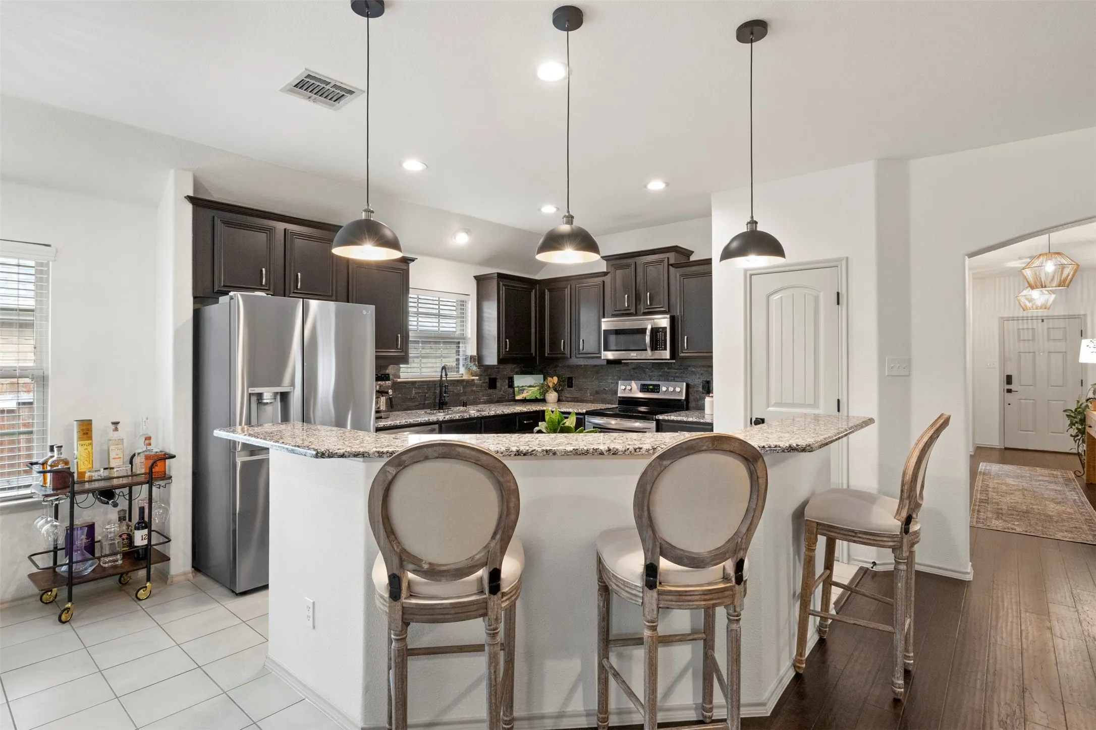 The kitchen combines granite countertops, dark cabinetry and stainless steel appliances with a NEW BACKSPLASH, UPDATED FIXTURES and MODERN LIGHTING for a refreshed, current look.
