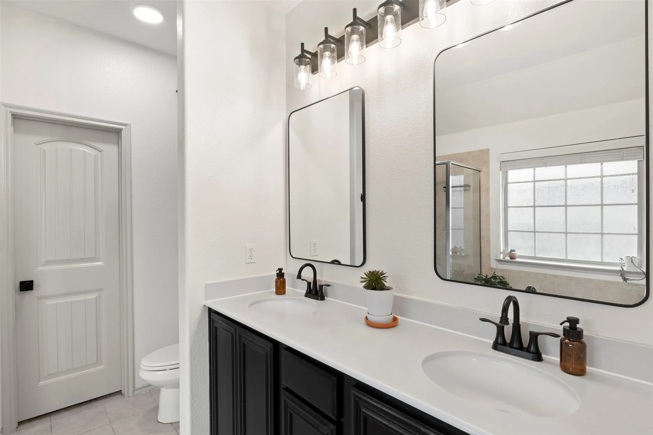 The long dual-sink vanity provides valuable counter space and storage, complemented by updated mirrors, lighting and matte-black fixtures.
