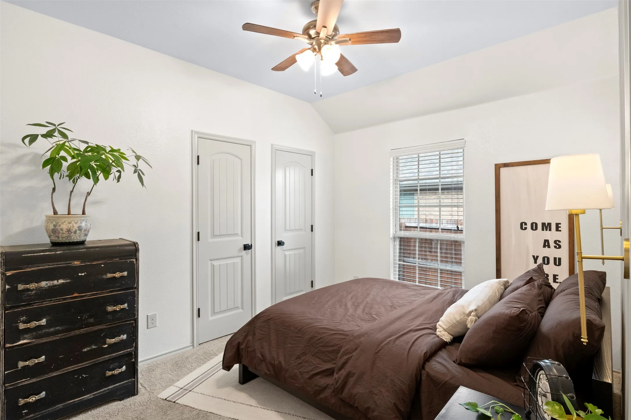 Secondary bedroom with a vaulted ceiling, neutral finishes, natural light and closet storage.