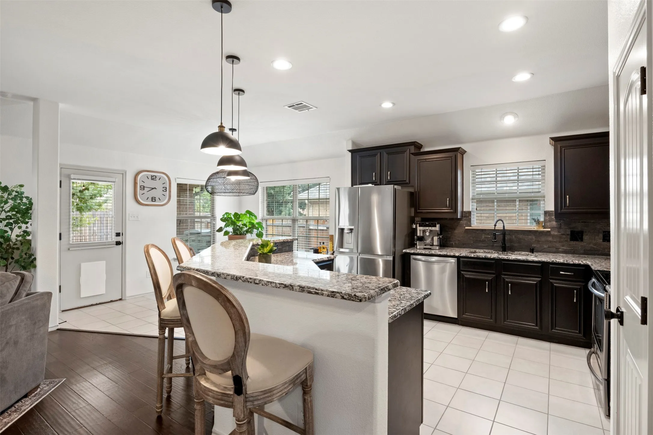 A closer look at the kitchen's updated finishes, including the dark backsplash, coordinating granite countertops and updated sink fixture, with natural light over the sink.