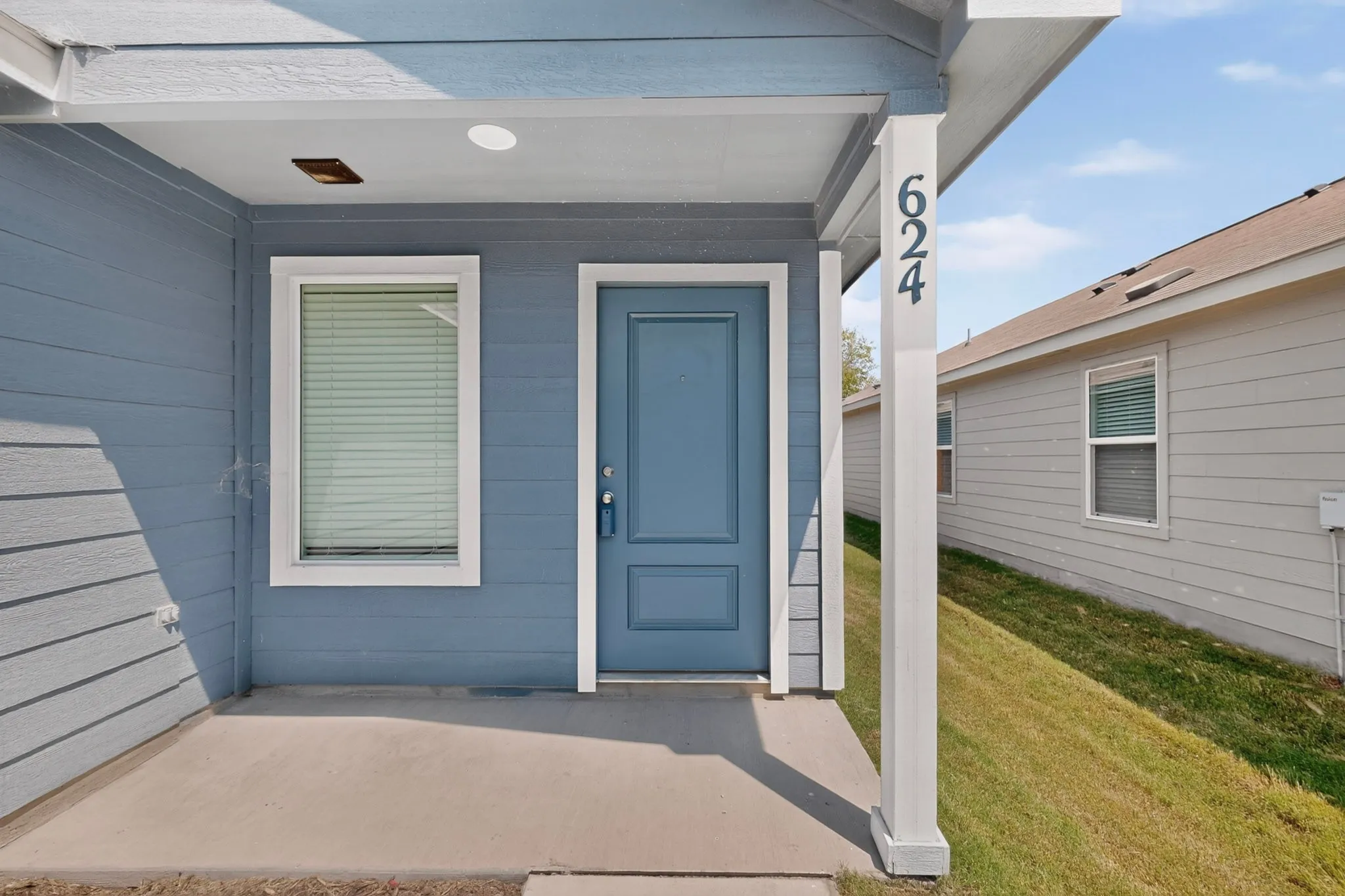 Entryway featuring a blue door, siding exterior, recessed lighting, and a concrete patio