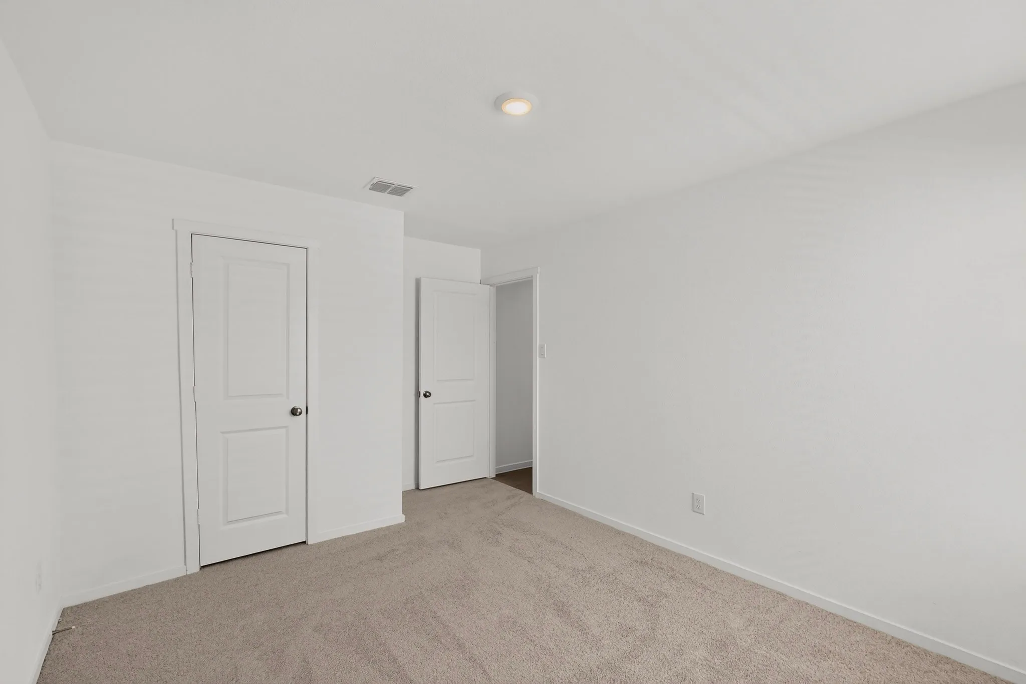 Neutral-toned carpeting, white walls, and white paneled doors