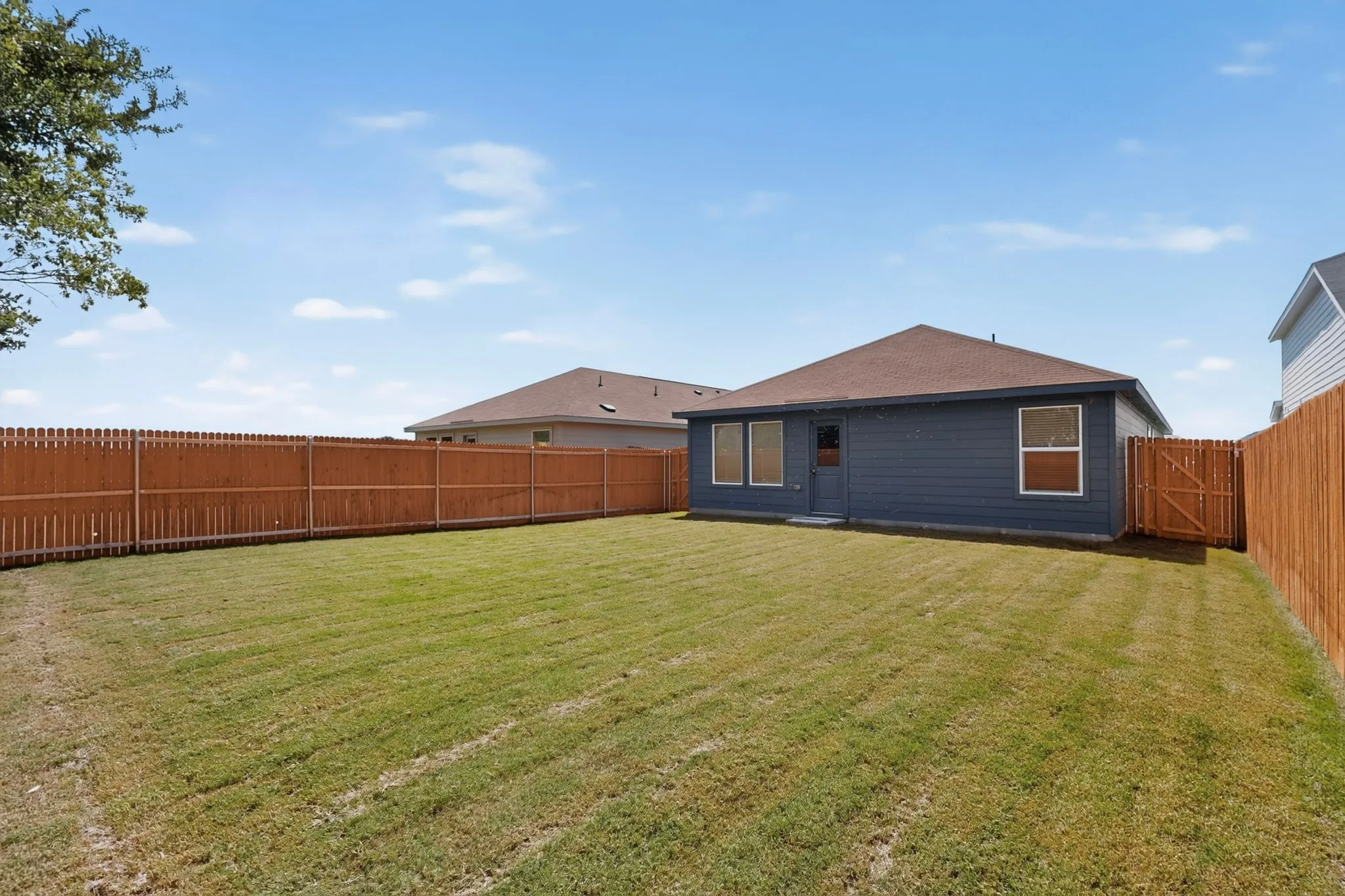 Fenced backyard with a blue exterior and a brown shingle roof