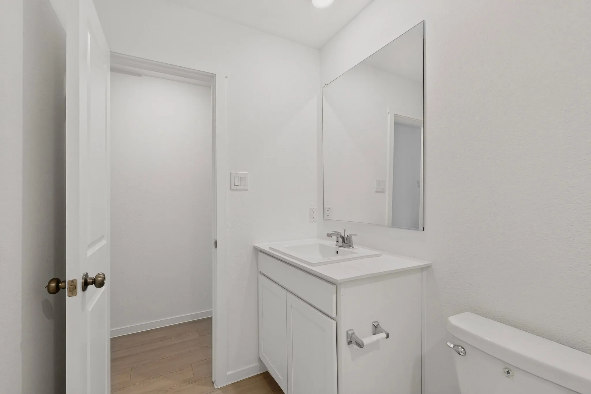 White vanity with integrated sink, chrome faucet, and a large wall-mounted mirror