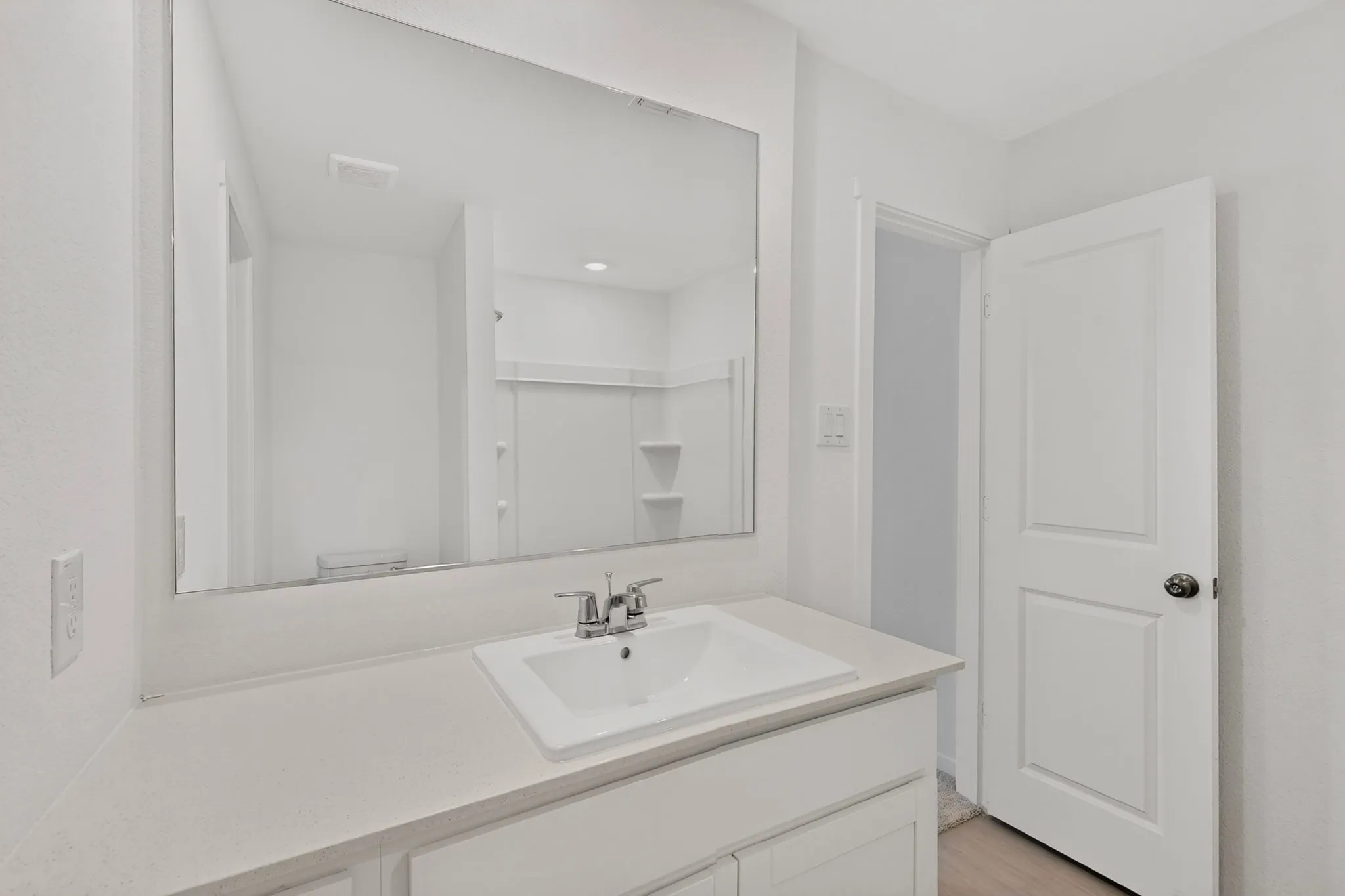 Bathroom featuring a rectangular undermount sink, dual-handle chrome faucet, light-toned countertop, and a large wall-mounted mirror