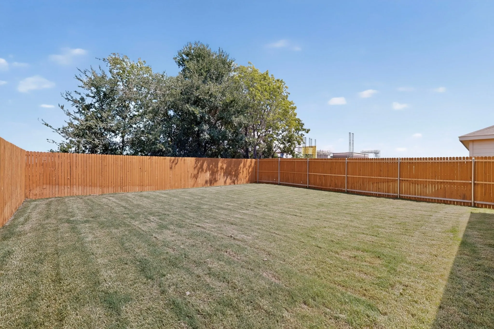 Expansive backyard featuring a manicured lawn and a privacy fence