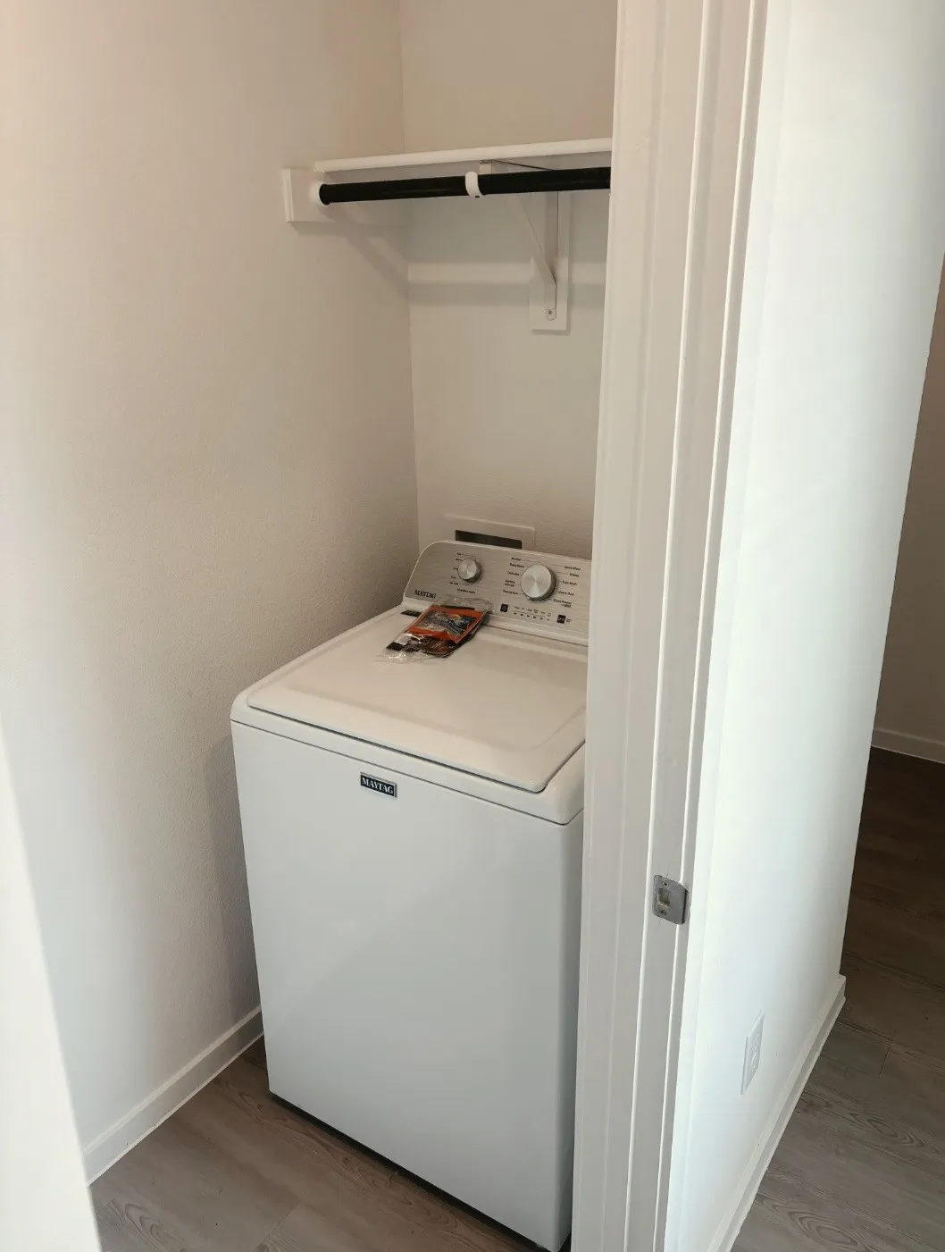 Laundry closet with a top-load washer, overhead shelving, and wood-finish flooring
