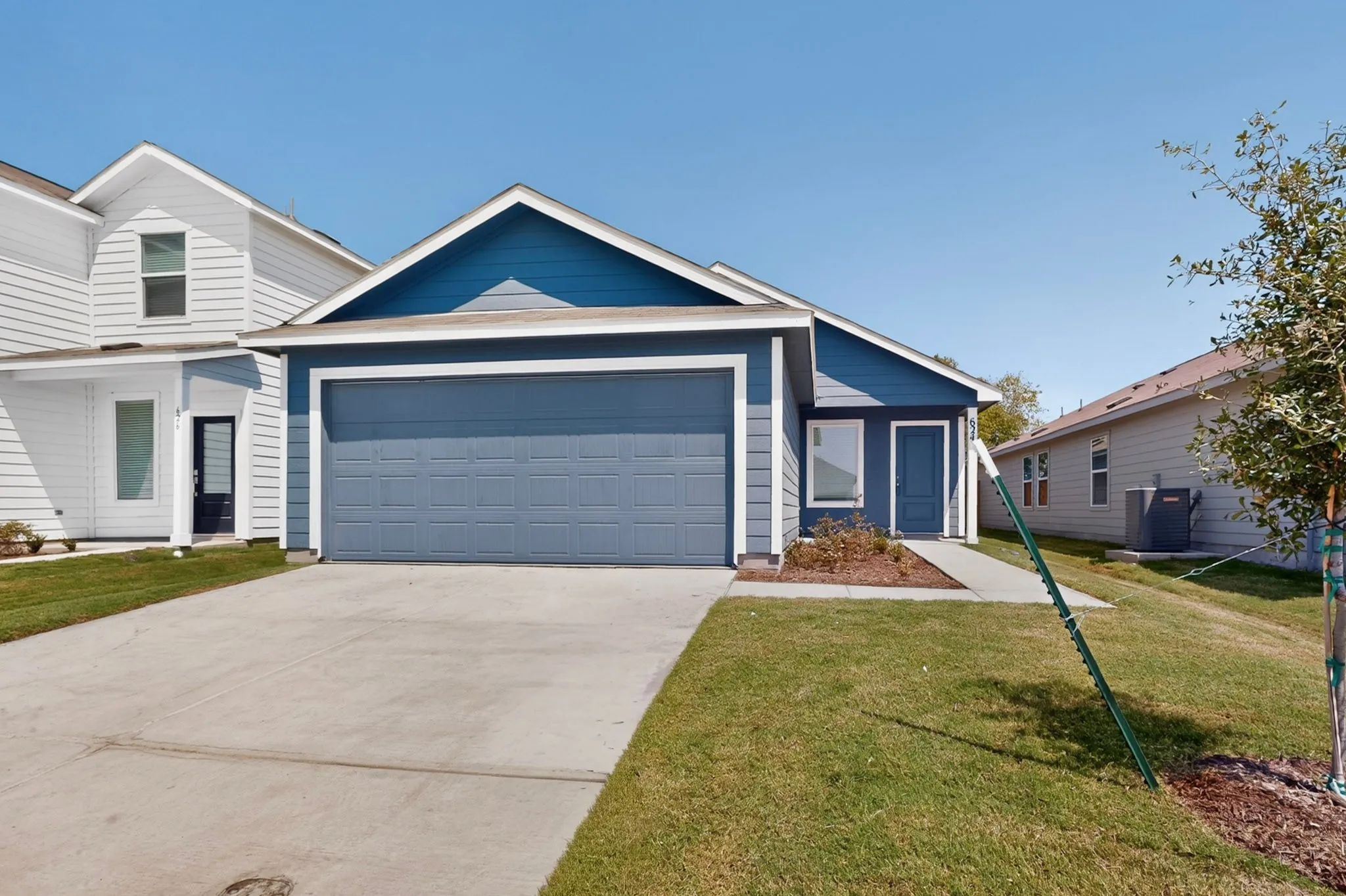 Contemporary facade with blue siding, attached garage, and concrete driveway