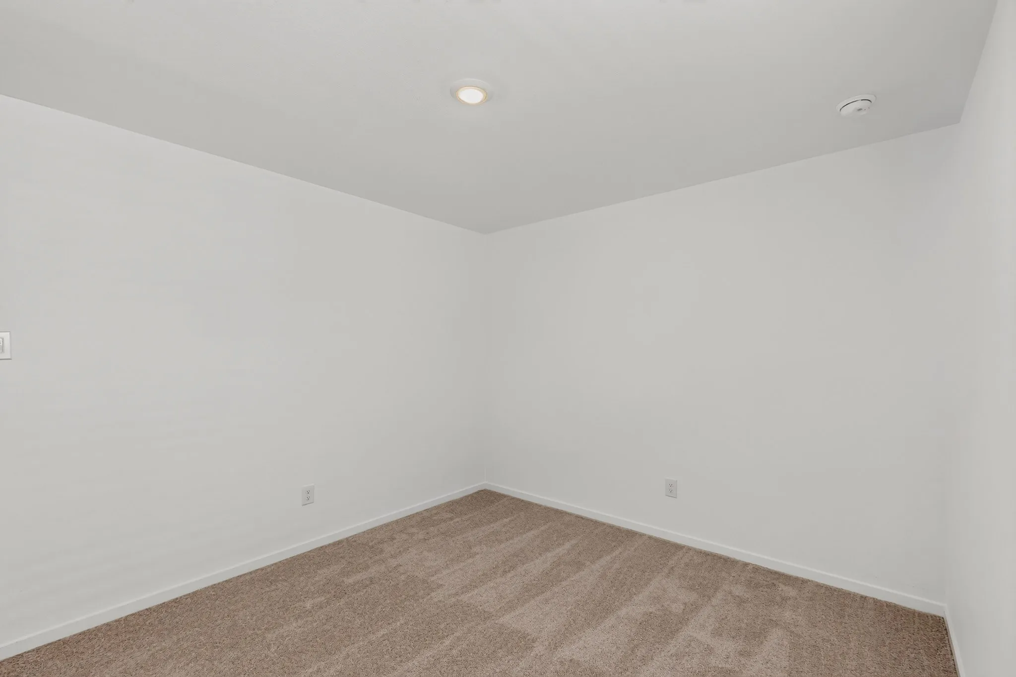 Recessed lighting, light-toned walls, and neutral carpeting