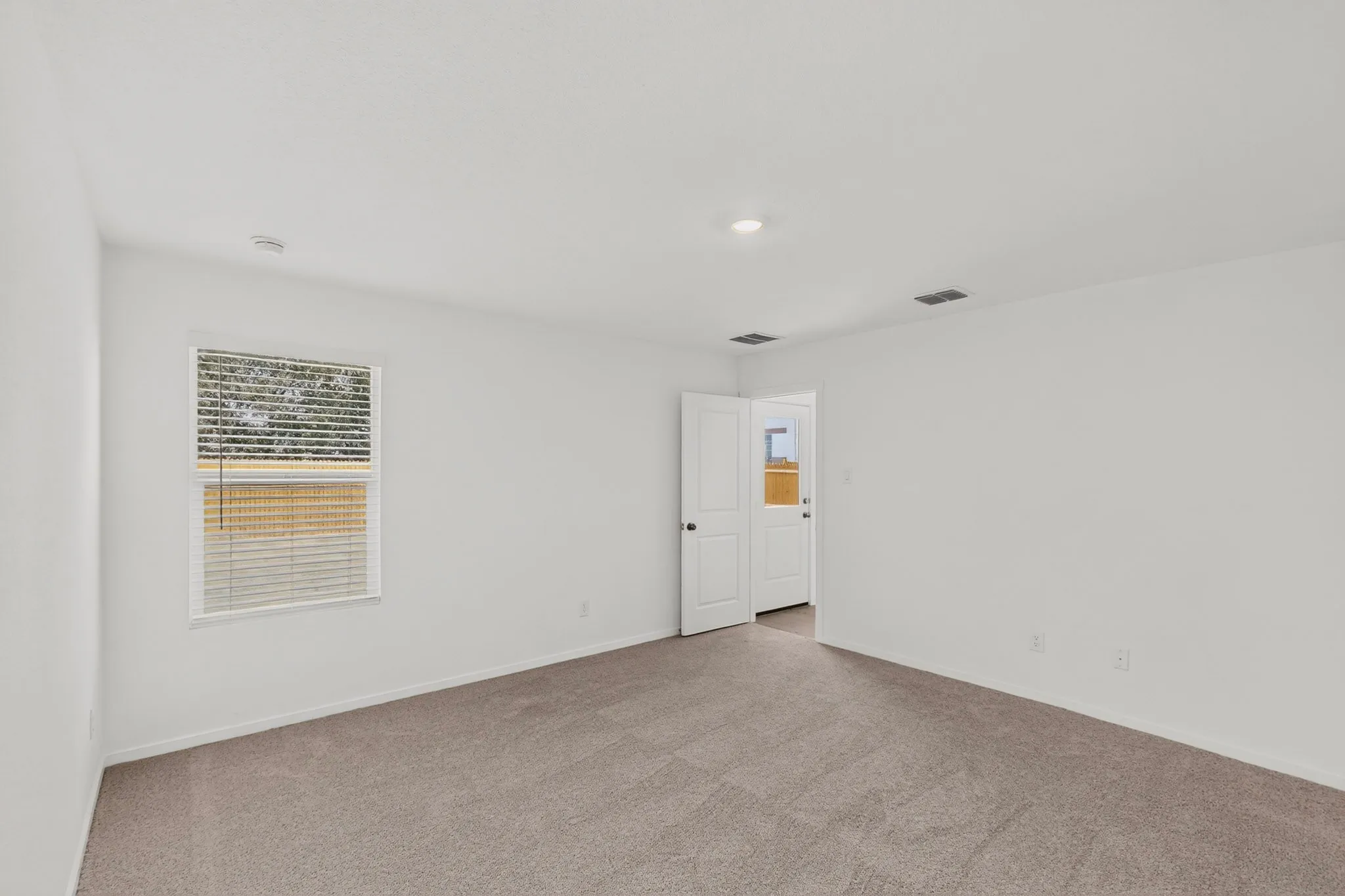 Neutral tone wall finishes, recessed lighting, and soft gray carpeting