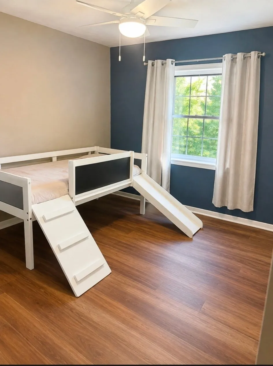 Room featuring wood-finish flooring, a ceiling fan with integrated lighting, and a window with white trim