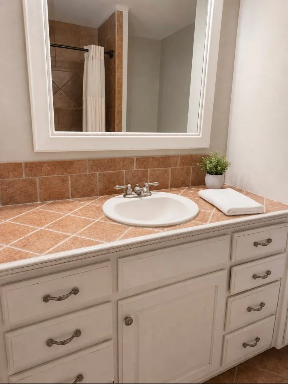 White vanity with ample storage, tiled countertop, and an integrated white basin
