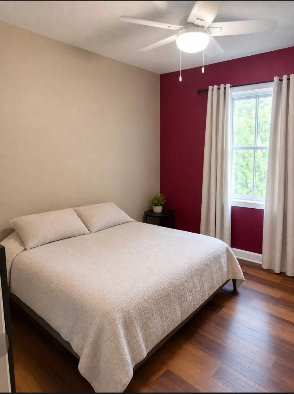 Wood-finish flooring, ceiling fan with integrated lighting, window with dark rod, and two-tone wall treatment