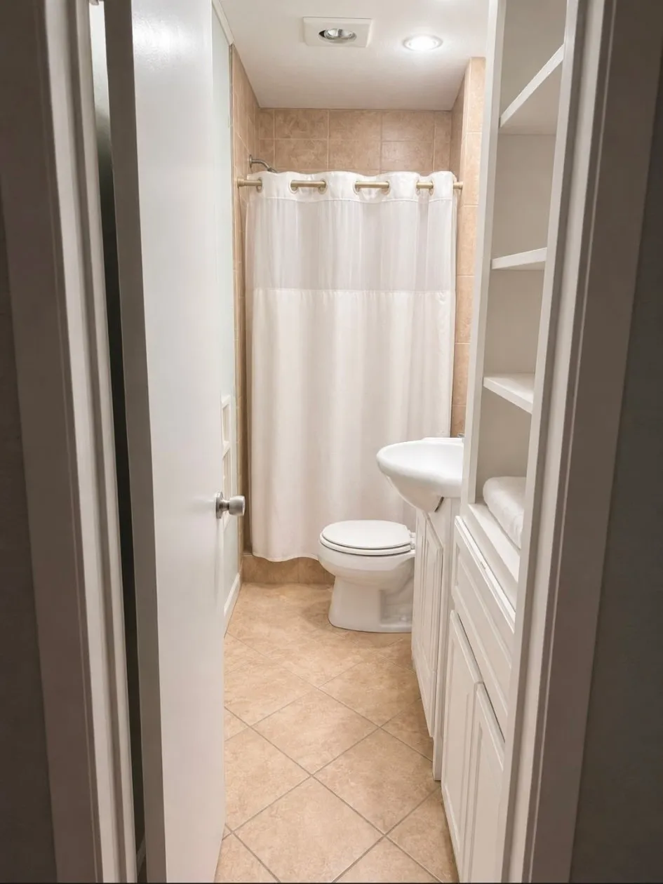 Full bathroom featuring tile flooring, a tiled shower surround, a built-in vanity with a basin sink, and integrated shelving