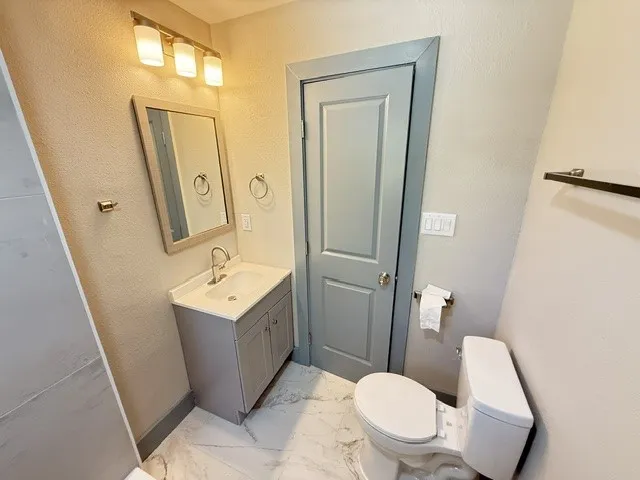 White countertop vanity with under-mount sink, brushed nickel faucet, and a framed mirror