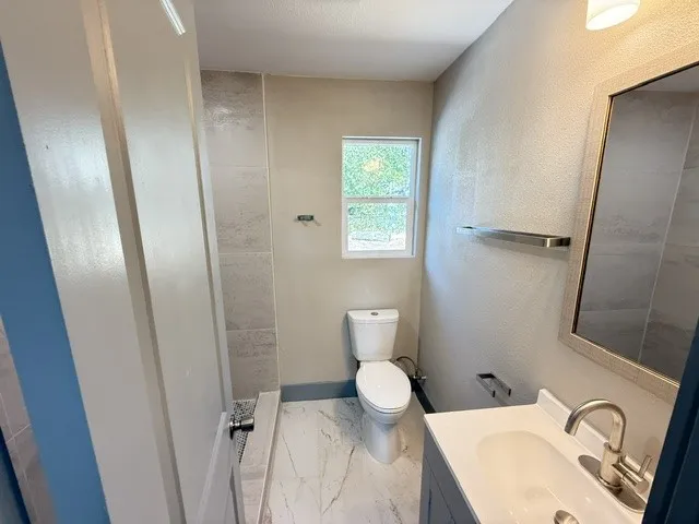 Modern bathroom featuring a single vanity with an integrated sink, brushed nickel faucet, and a wall-mounted mirror