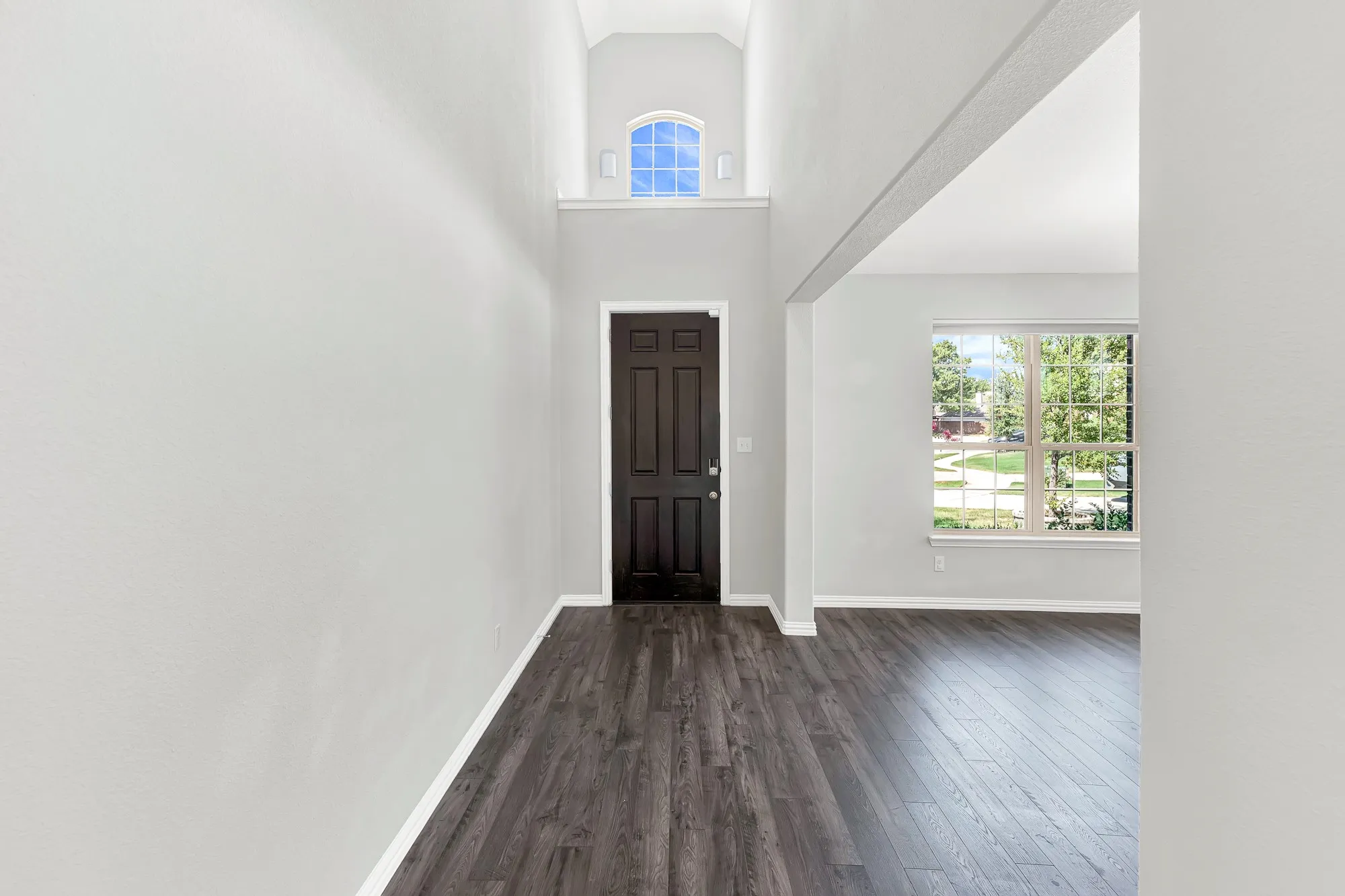 Entryway featuring wood-finish flooring, a dark-paneled door, and a transom window
