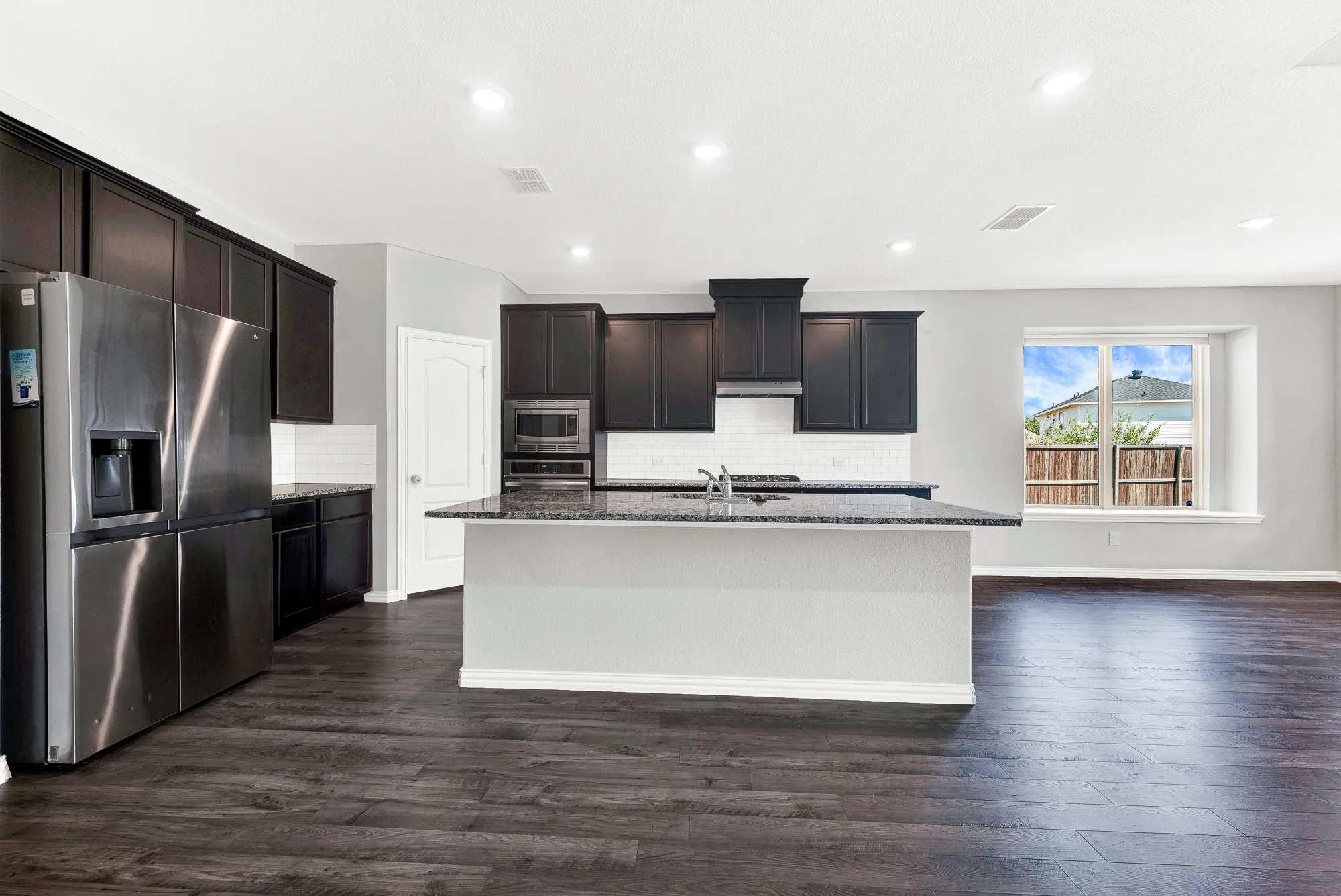 Gourmet kitchen featuring dark cabinetry, stainless steel appliances, and a large center island with gray countertops