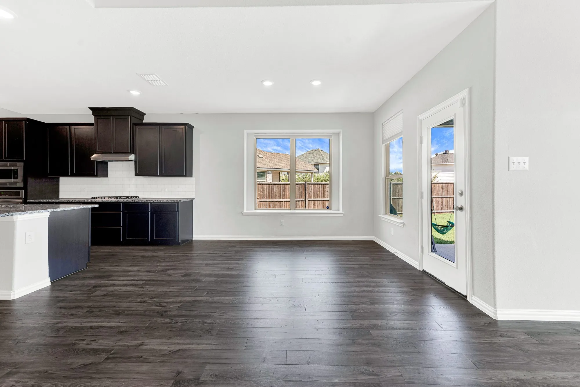 Open-concept living and kitchen area featuring dark wood-finish cabinetry, stainless steel appliances, recessed ceiling lighting, and dark wood-finish plank flooring throughout