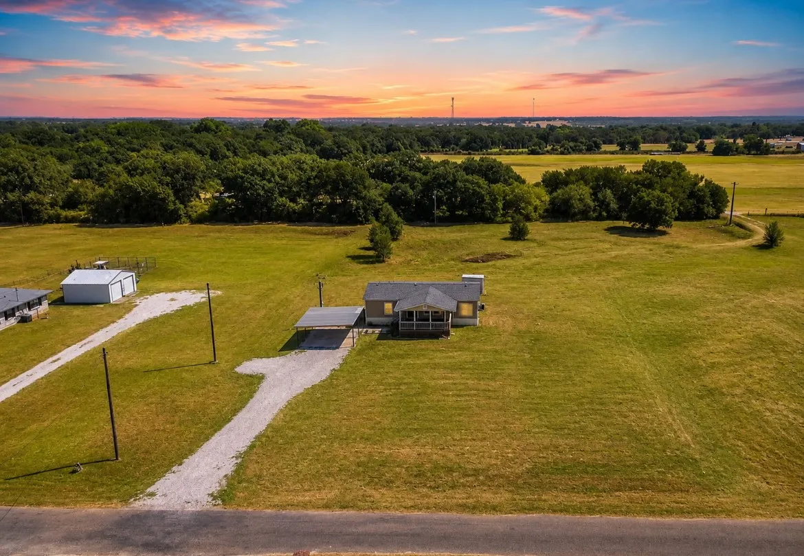 Expansive lot with a single-story residence, gravel driveway, and detached carport