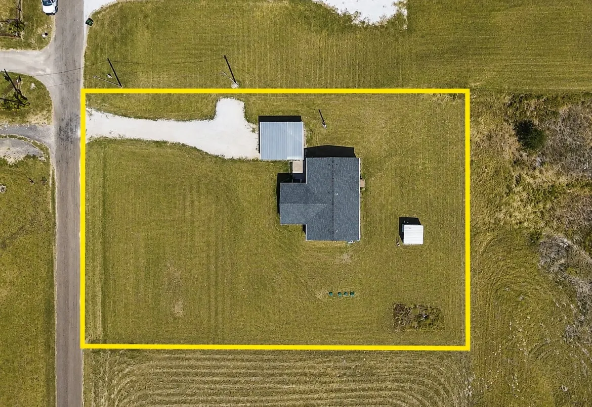 Expansive property featuring a gravel driveway, detached shed, and additional outbuilding, all set on a generous grass lot