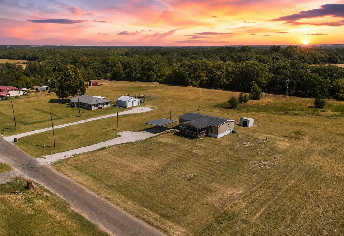 Expansive property featuring two residences, a detached garage, a storage shed, and a covered carport, all surrounded by abundant natural landscaping