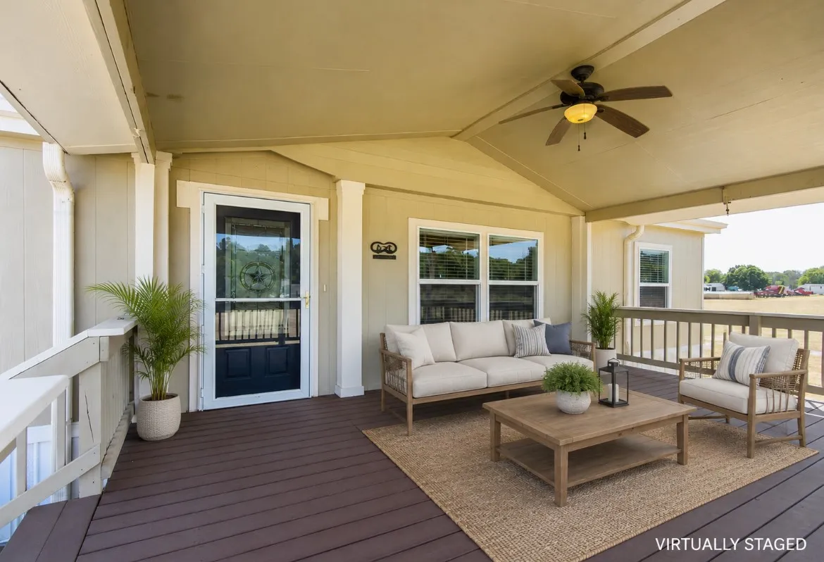 Expansive covered porch featuring a ceiling fan with integrated lighting, wood-finish decking, and light-toned exterior siding