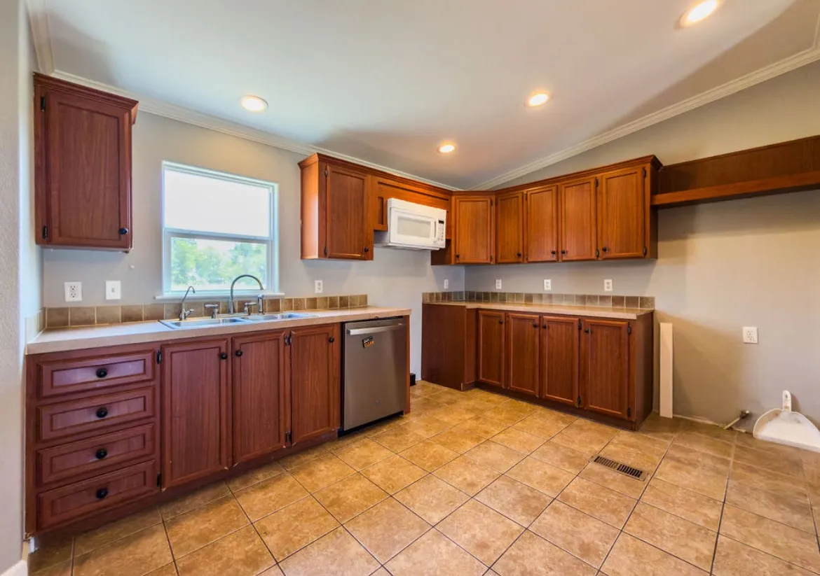 Kitchen featuring wood-finish cabinetry, tile flooring, recessed lighting, and a stainless steel dishwasher