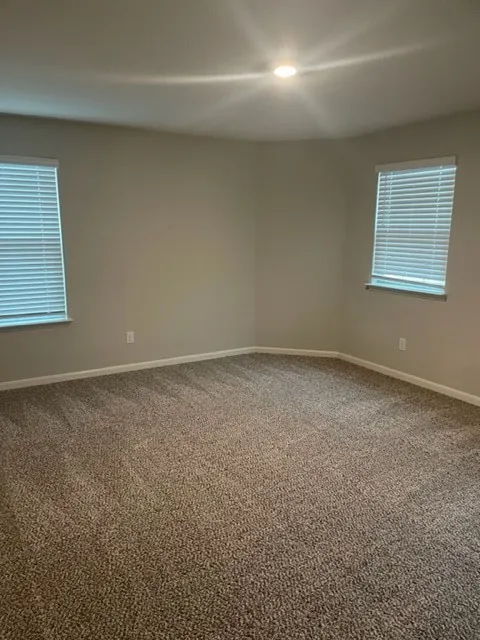 Neutral-toned carpeting, recessed lighting, and dual windows with blinds