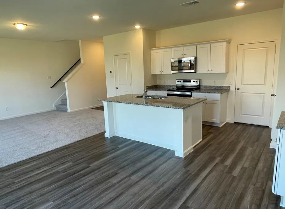 Kitchen featuring a central island, white cabinetry, integrated stainless steel microwave, and a black range