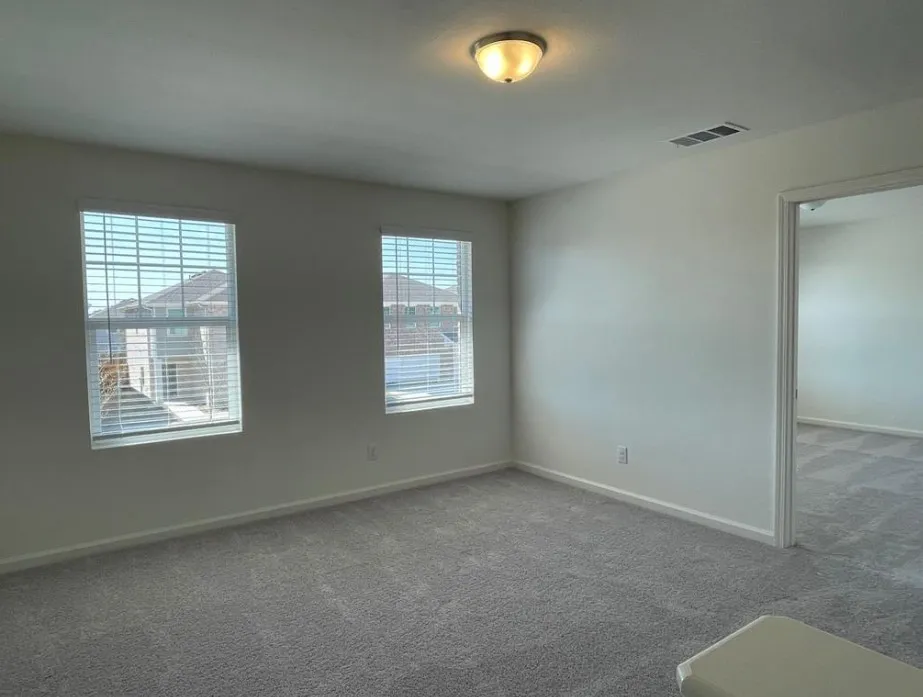 Bright interior with neutral carpeting and a semi-flush mount ceiling fixture
